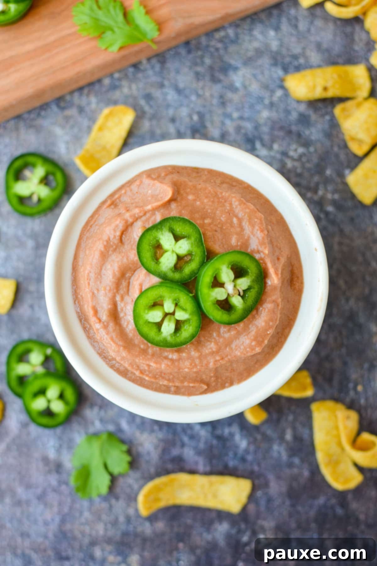 Craveable Homemade Fritos Bean Dip 6 A bowl of bean dip garnished with jalapeno slices on top.