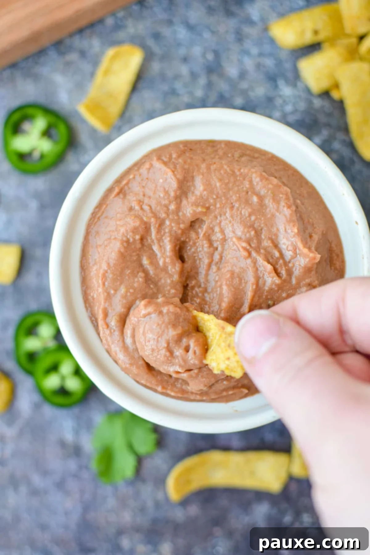 Craveable Homemade Fritos Bean Dip 7 Dipping a corn chip into bean dip.