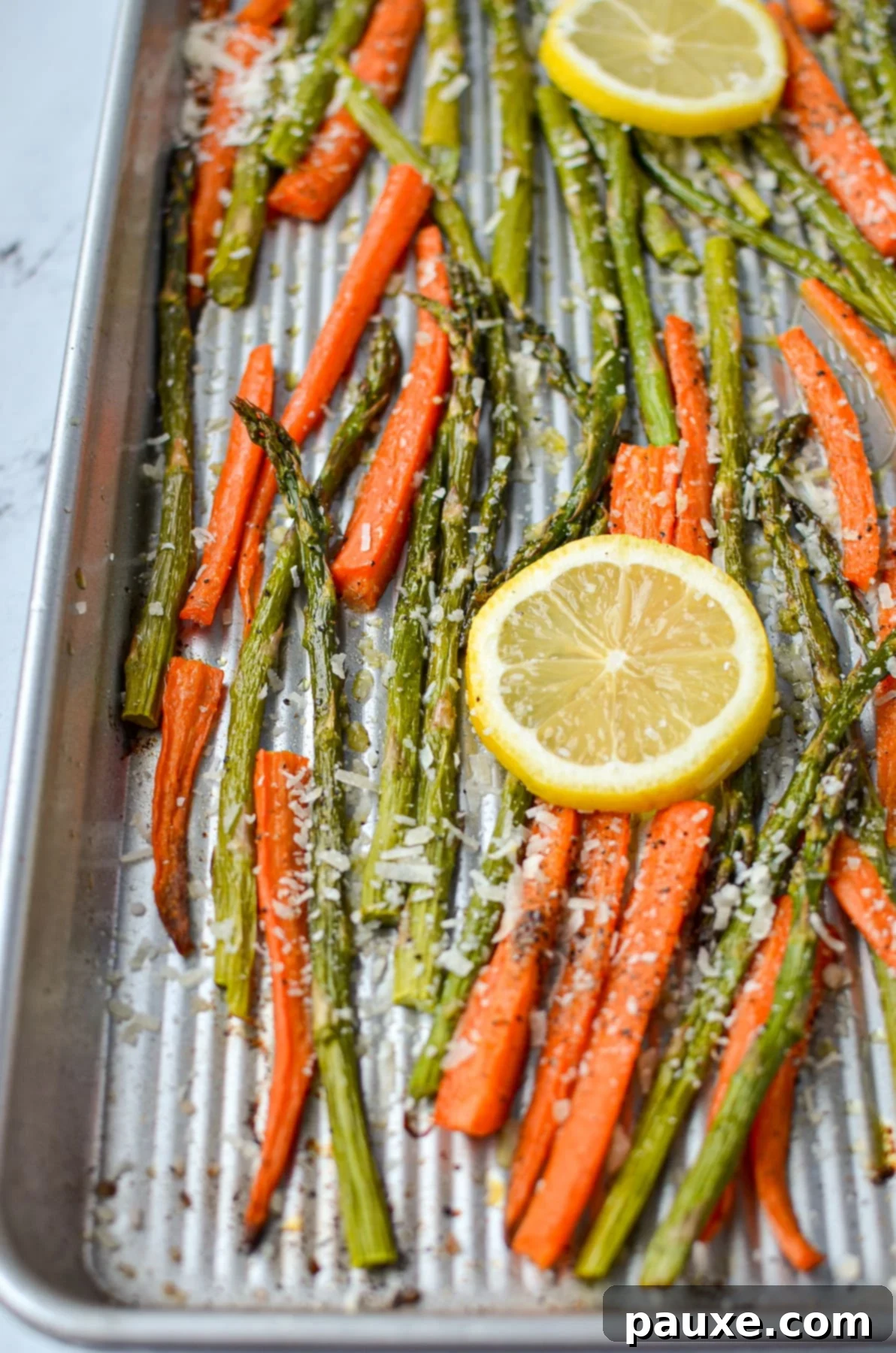 Garlic Herb Roasted Asparagus and Carrots 2 A sheet pan with asparagus and carrots, garnished with lemon slices, ready to be served.
