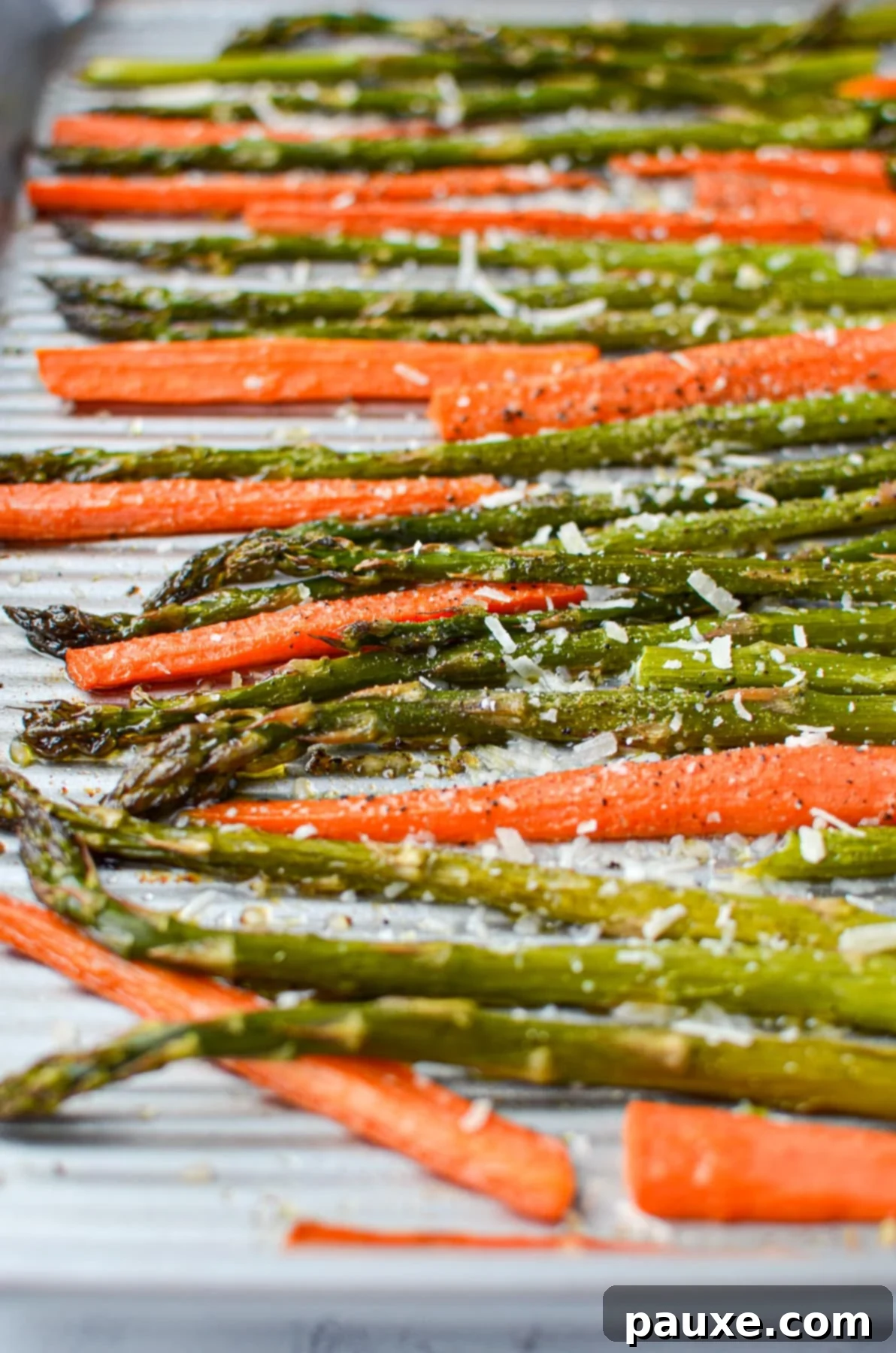 Garlic Herb Roasted Asparagus and Carrots 6 A sheet pan with roasted asparagus and carrots, garnished with grated parmesan cheese, ready to serve.