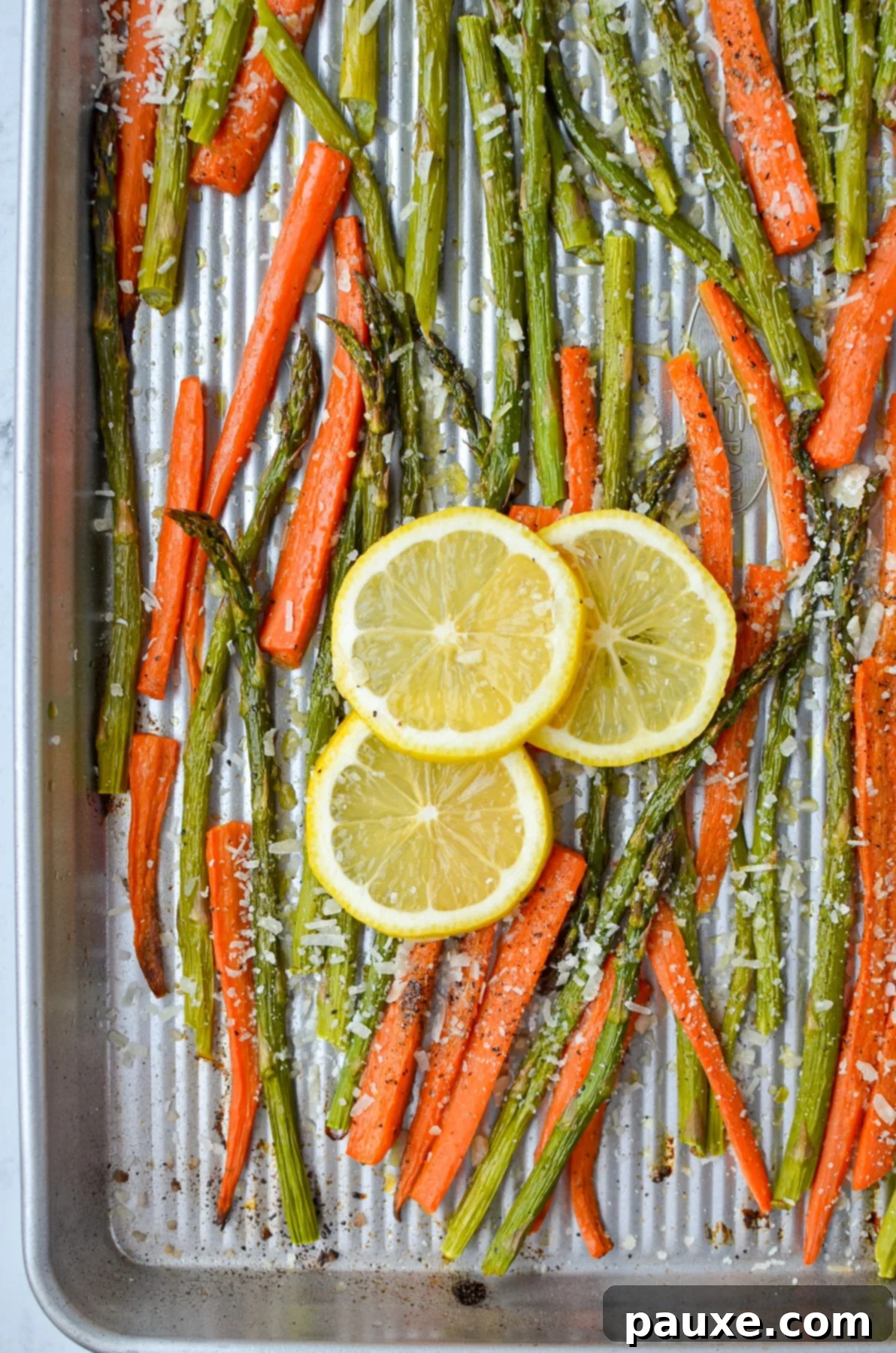 Garlic Herb Roasted Asparagus and Carrots 7 A sheet pan with roasted vegetables garnished with lemon wedges and fresh herbs.