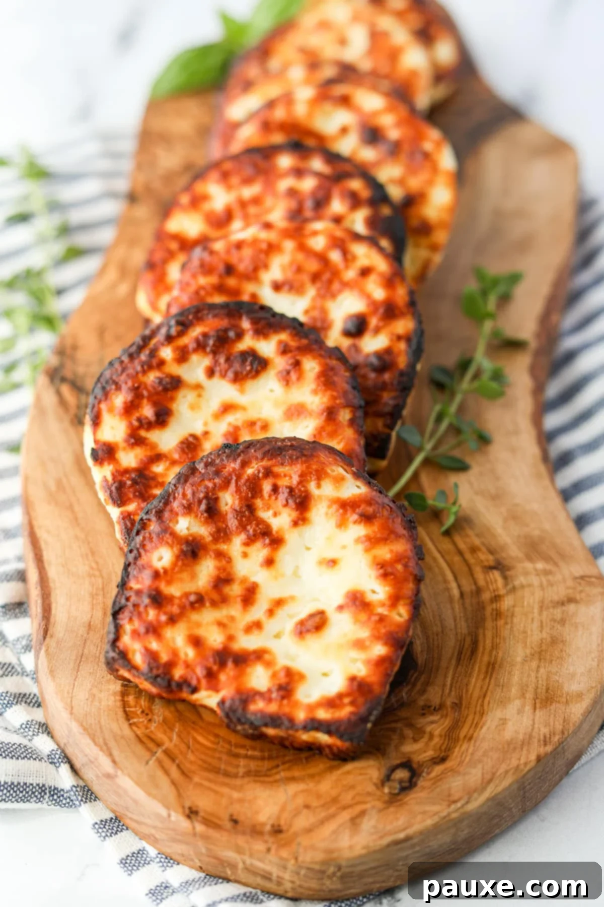 Golden Air Fryer Halloumi 2 Slices of golden-brown fried halloumi cheese on a rustic wooden board, garnished with fresh herbs.