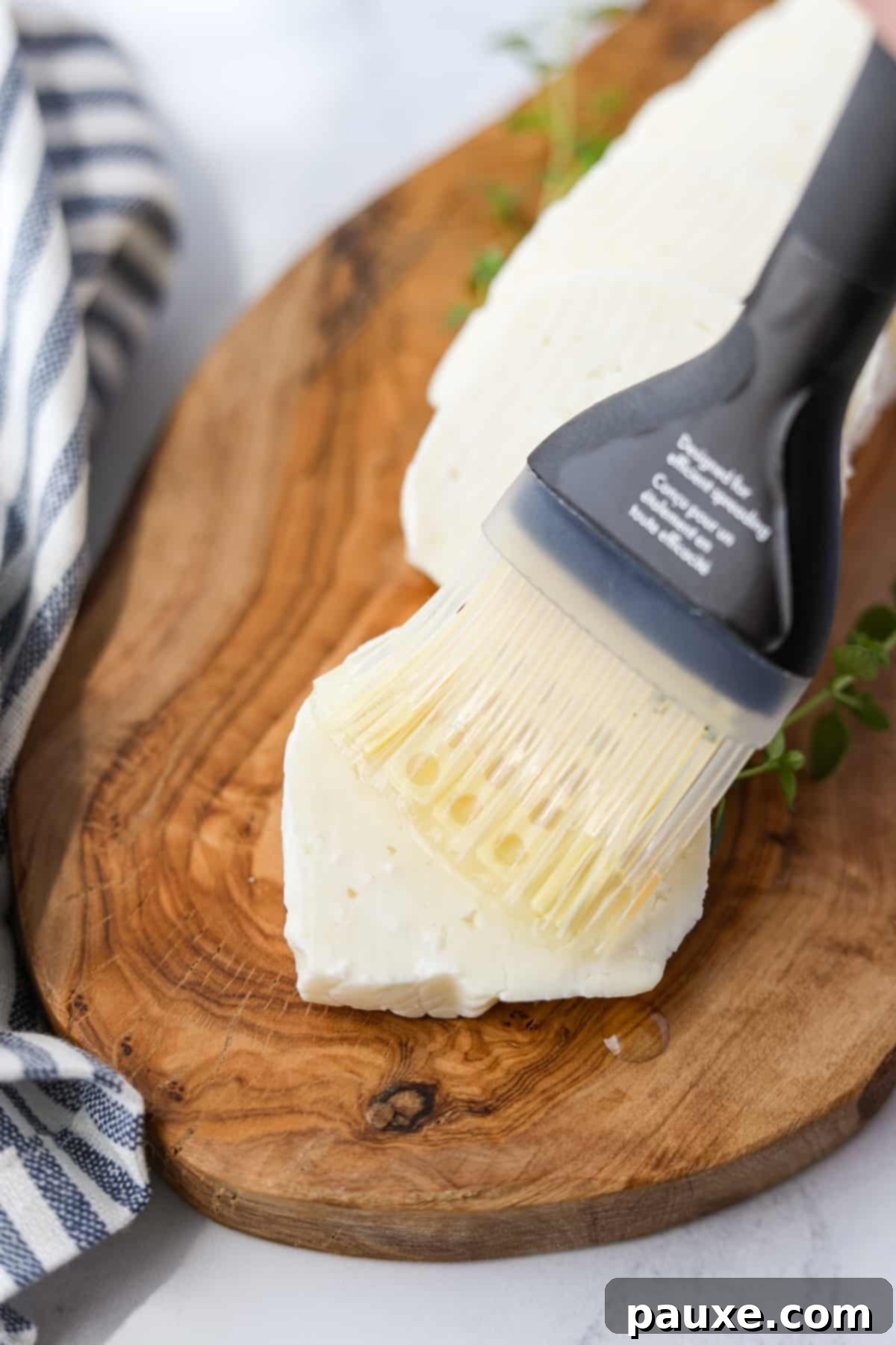 Golden Air Fryer Halloumi 4 Brushing a thin layer of avocado oil onto a freshly sliced piece of Halloumi cheese, preparing it for air frying.