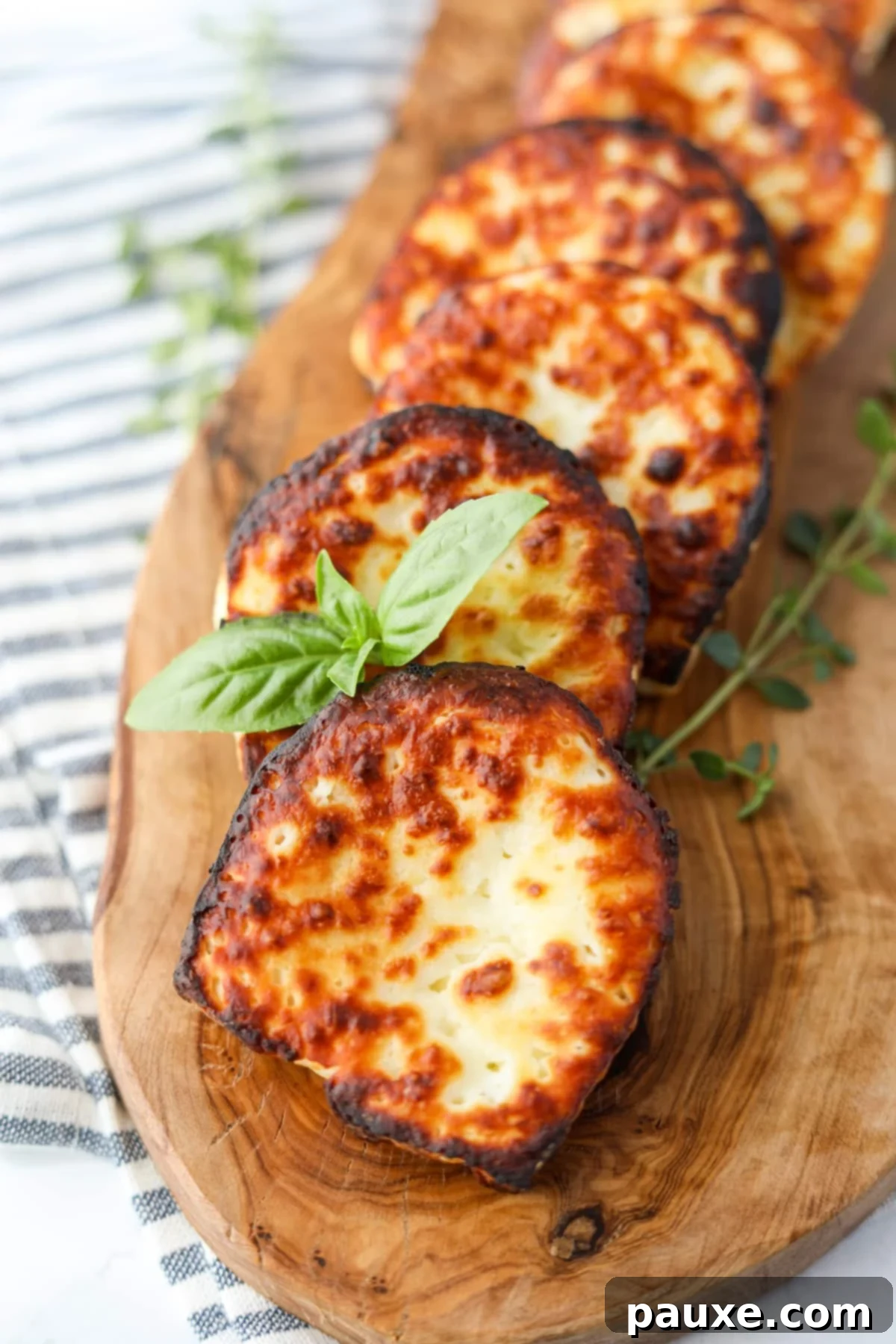 Golden Air Fryer Halloumi 7 A serving of golden-brown air-fried Halloumi cheese on a wooden board, elegantly garnished with fresh basil leaves.