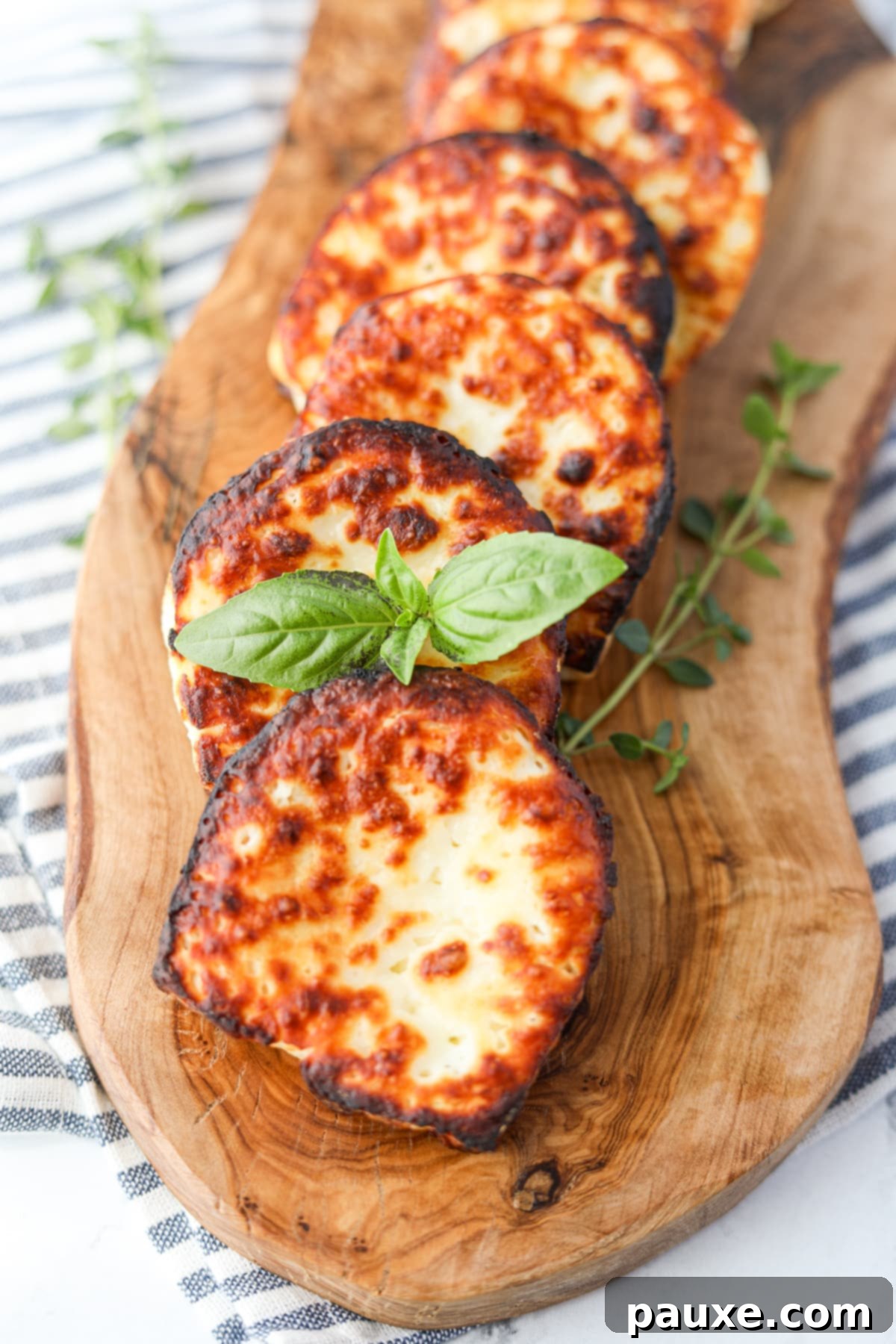 Golden Air Fryer Halloumi 9 A hand garnishing a slice of freshly air-fried Halloumi cheese with vibrant fresh basil leaves, ready to be served.