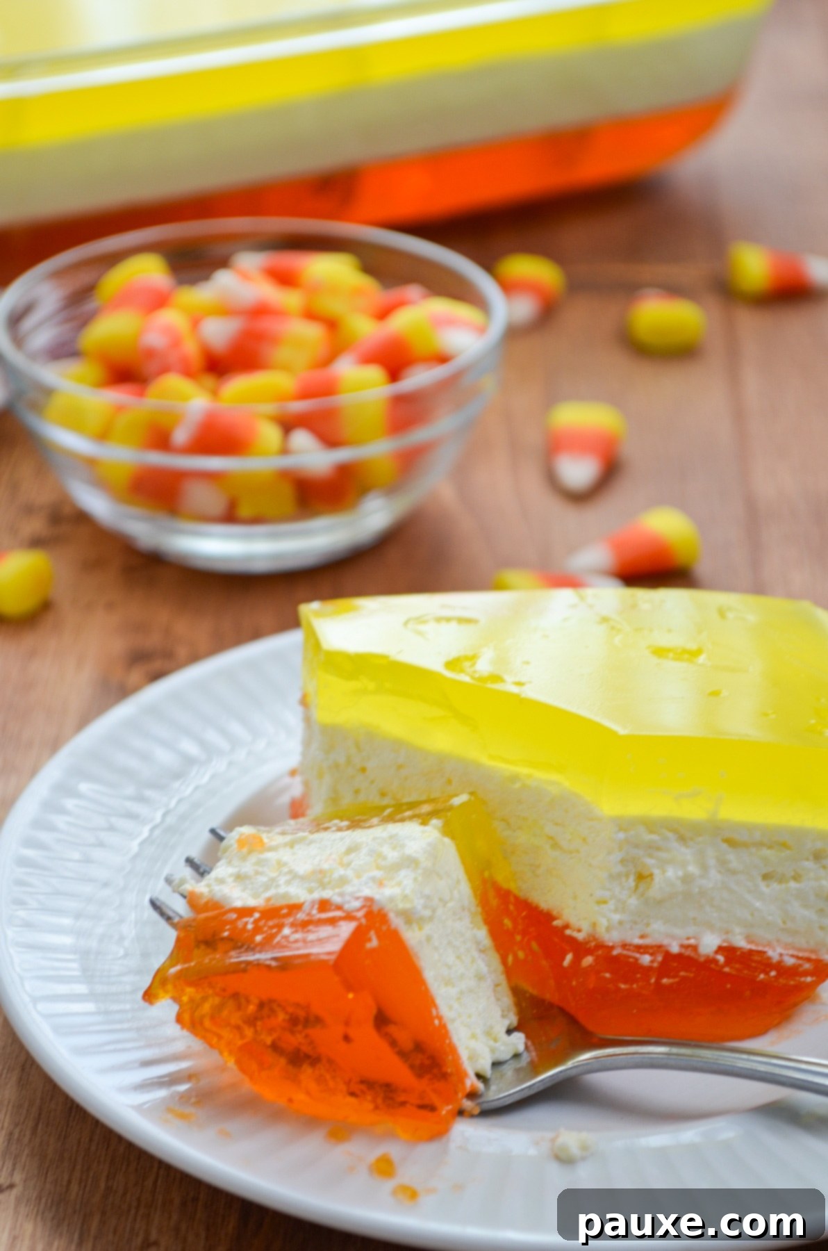 Spooky Layered Gelatin 2 A perfectly sliced piece of layered Halloween Jello, showcasing its vibrant orange, creamy white, and bright yellow layers.
