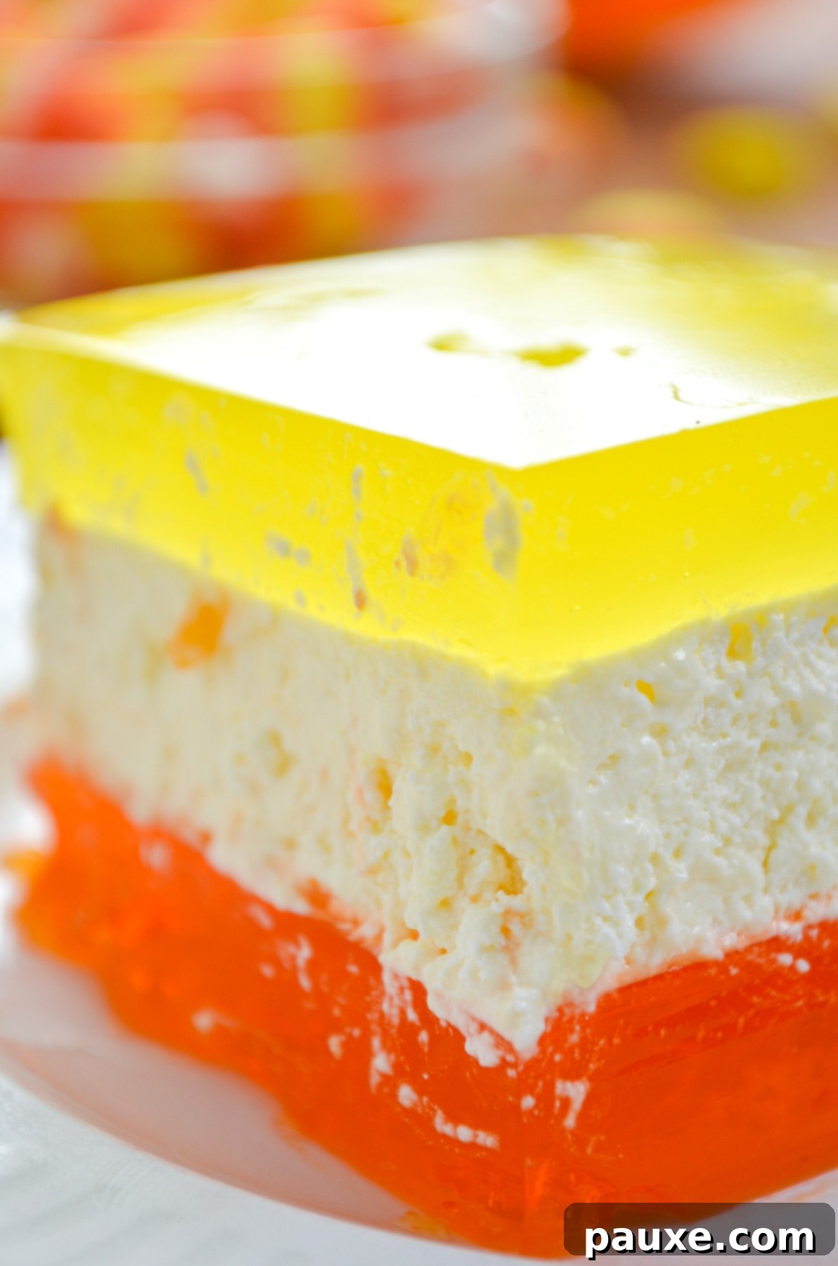 Spooky Layered Gelatin 14 A vibrant Halloween layered Jell-O dessert showing distinct orange, creamy white, and lemon yellow layers.