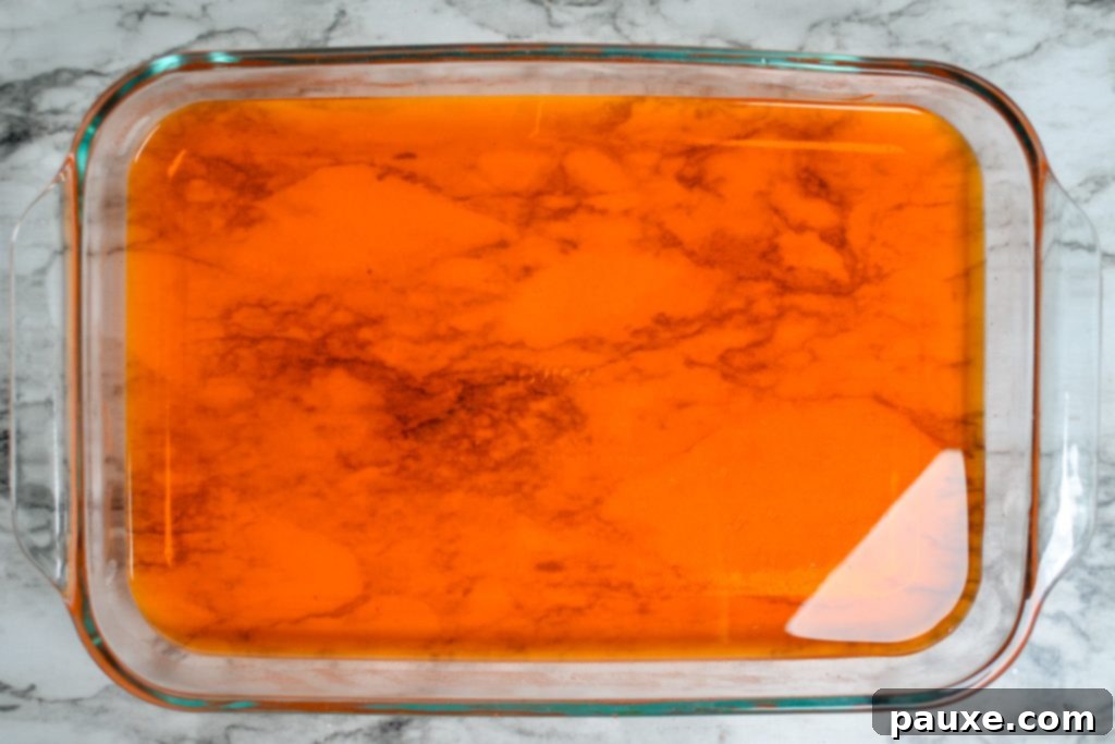 Spooky Layered Gelatin 6 The orange Jell-O layer neatly poured and settling at the bottom of a clear glass baking dish.