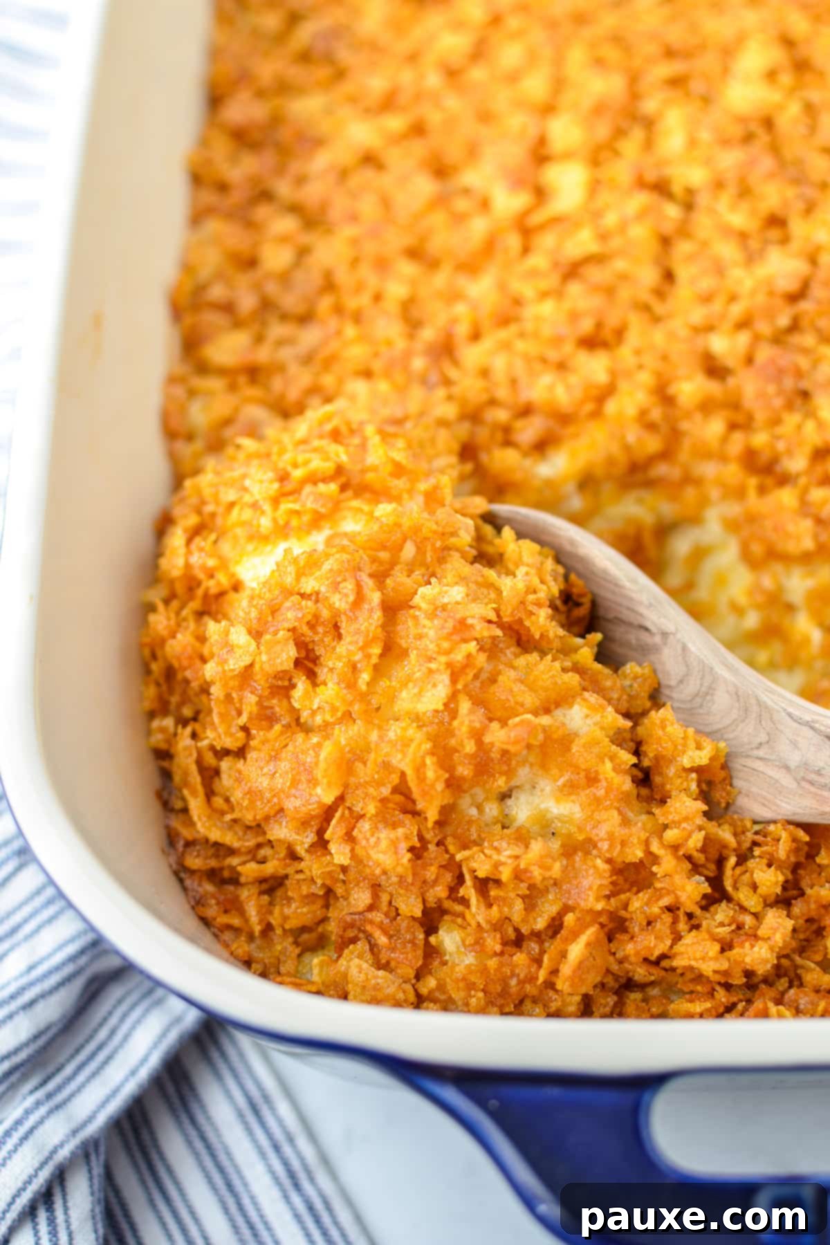 Effortless Cheesy Funeral Potatoes 2 Scooping out hash brown casserole with a wooden spoon.
