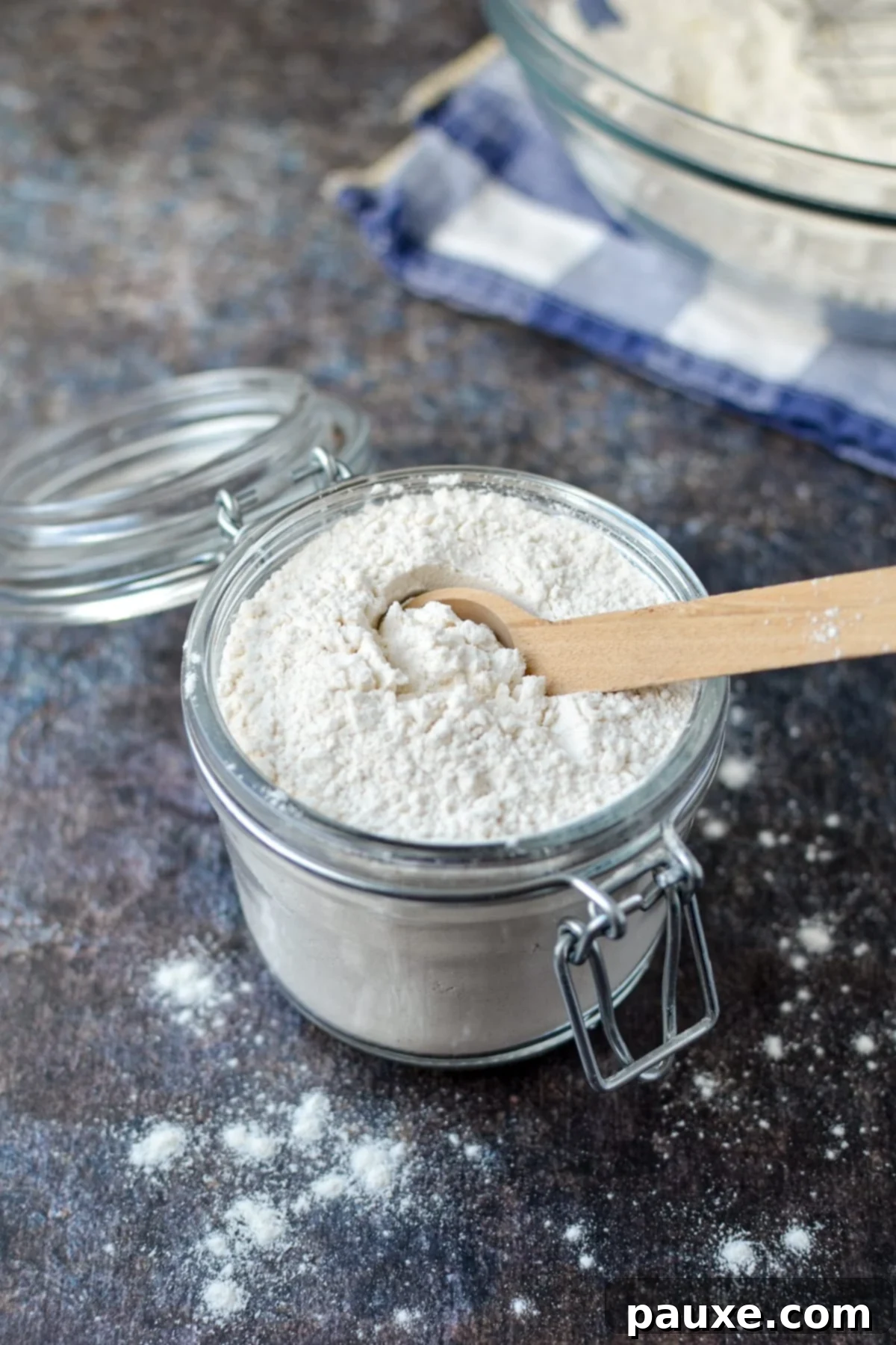 Homemade Self-Rising Flour in Minutes 7 A small jar of flour with a wooden spoon sticking out, ready for baking.