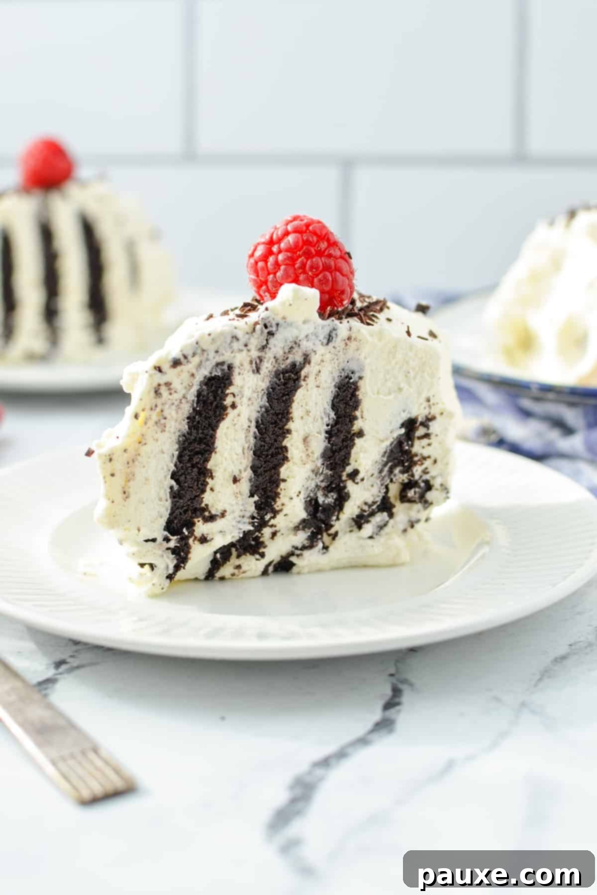 No-Bake Chocolate Wafer Zebra Delight 8 A perfectly diagonal slice of Chocolate Wafer Icebox Cake, showcasing its striking striped interior, elegantly topped with a single fresh raspberry.