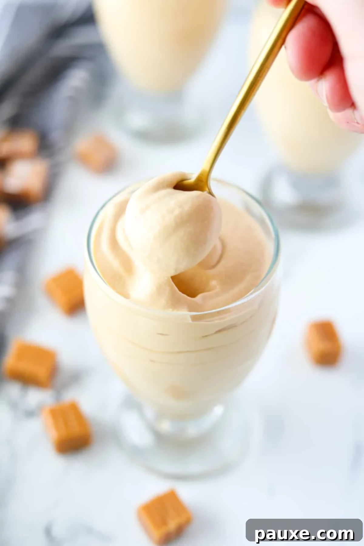 Decadent Dulce De Leche Cloud 2 A golden spoon delicately scoops a portion of creamy dulce de leche mousse from an elegant glass jar, highlighting its rich texture and inviting appearance.
