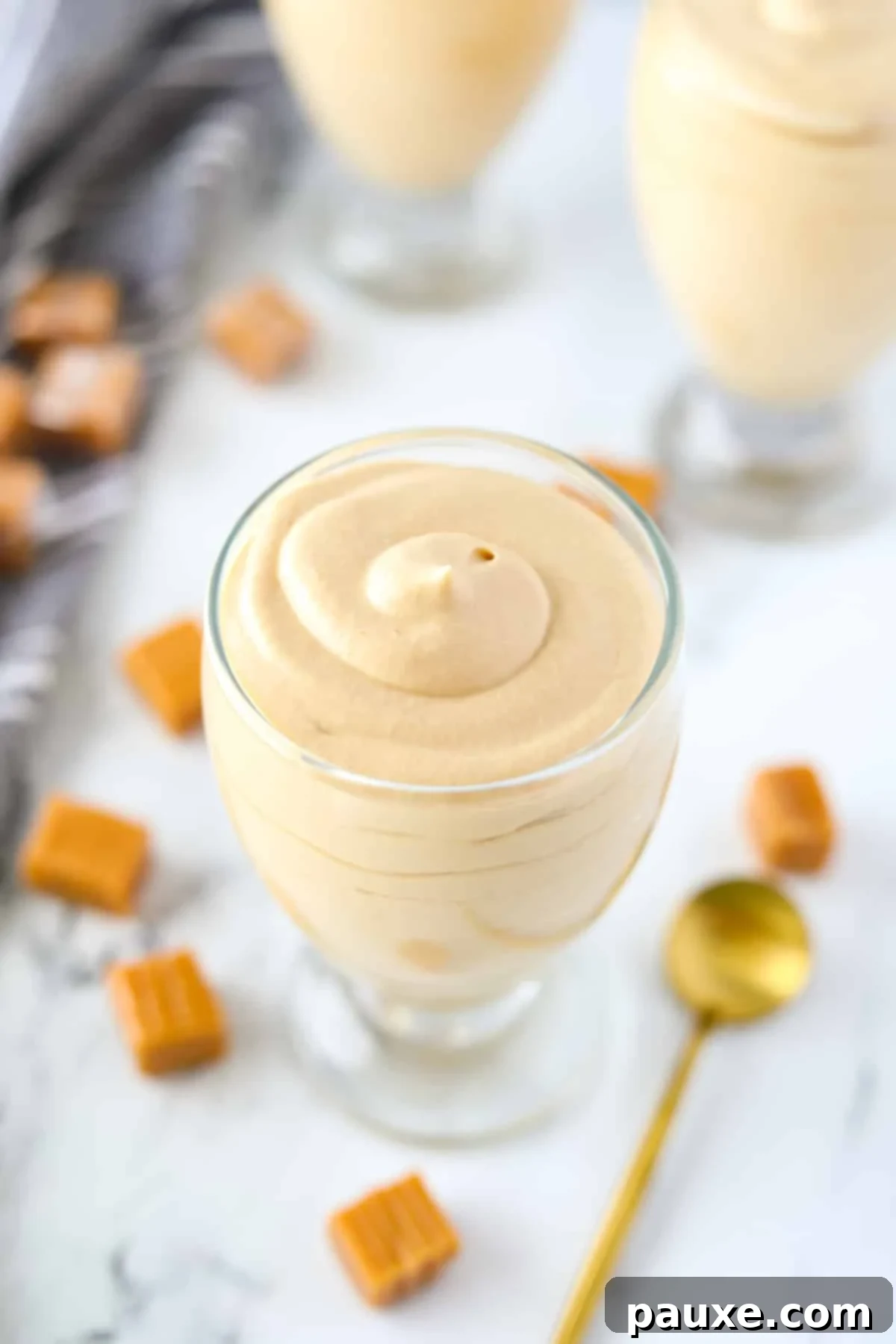 Decadent Dulce De Leche Cloud 9 An inviting jar of creamy dulce de leche mousse, with a golden spoon resting elegantly on its side, ready to be scooped and enjoyed.