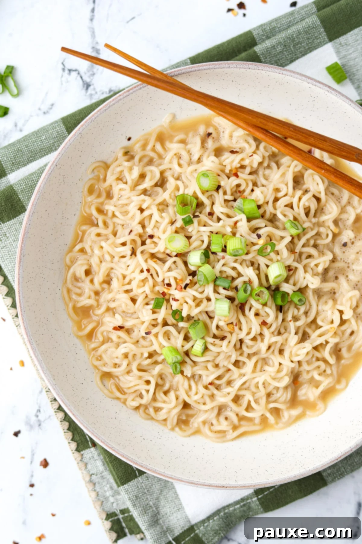 Kylie Jenner's Famous Ramen Hack 2 A beautifully presented bowl of Kylie Jenner's ramen, garnished with vibrant red pepper flakes and freshly chopped green onions, ready to be enjoyed.