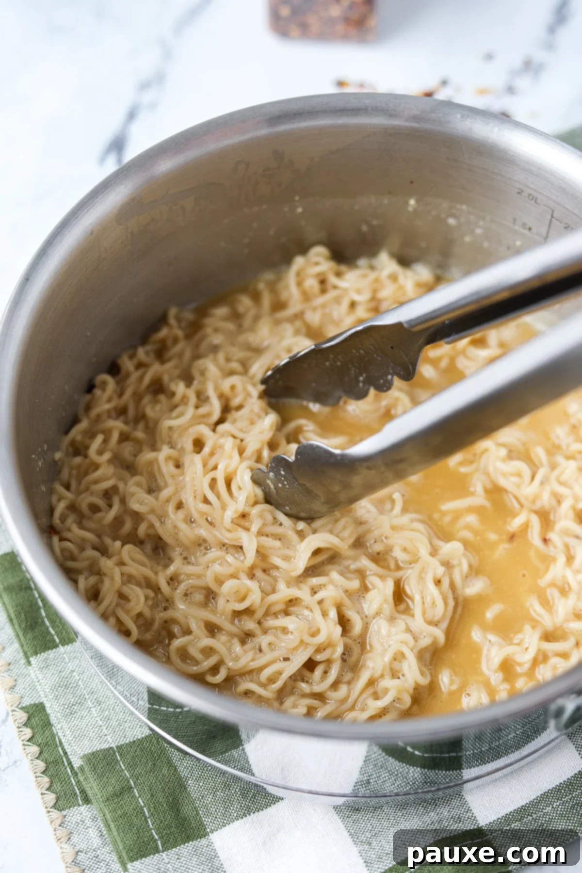 Kylie Jenner's Famous Ramen Hack 6 A skillet of creamy ramen noodles being stirred, showing the luscious, smooth sauce that envelops the noodles.