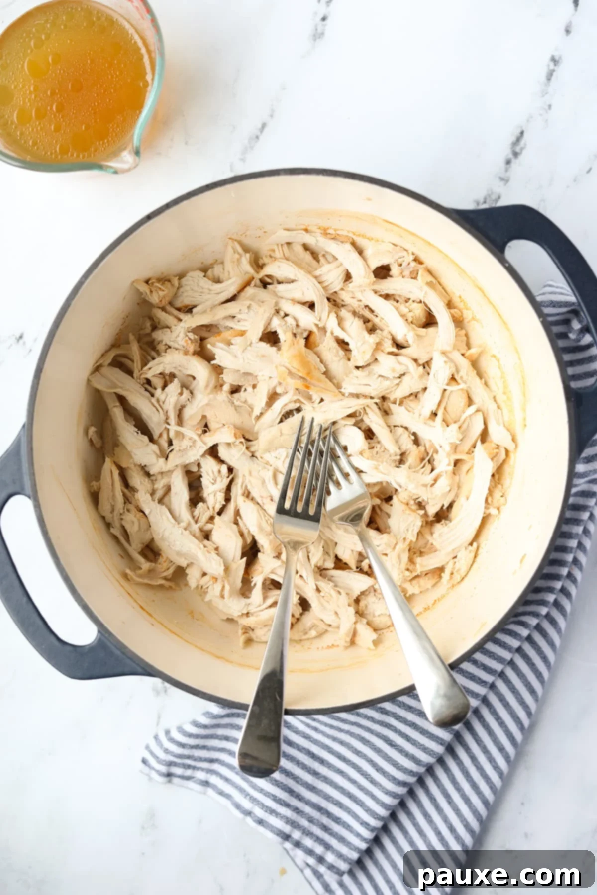 Ultimate Dutch Oven Pulled Chicken 2 A Dutch Oven with two forks and perfectly shredded chicken inside, ready for use.