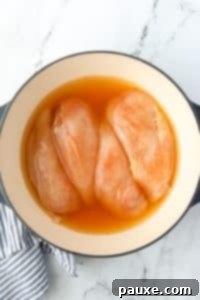 Ultimate Dutch Oven Pulled Chicken 13 A Dutch Oven with broth-covered chicken breasts.