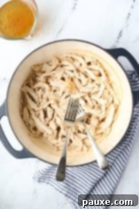 Ultimate Dutch Oven Pulled Chicken 15 A Dutch Oven with two forks and shredded chicken.