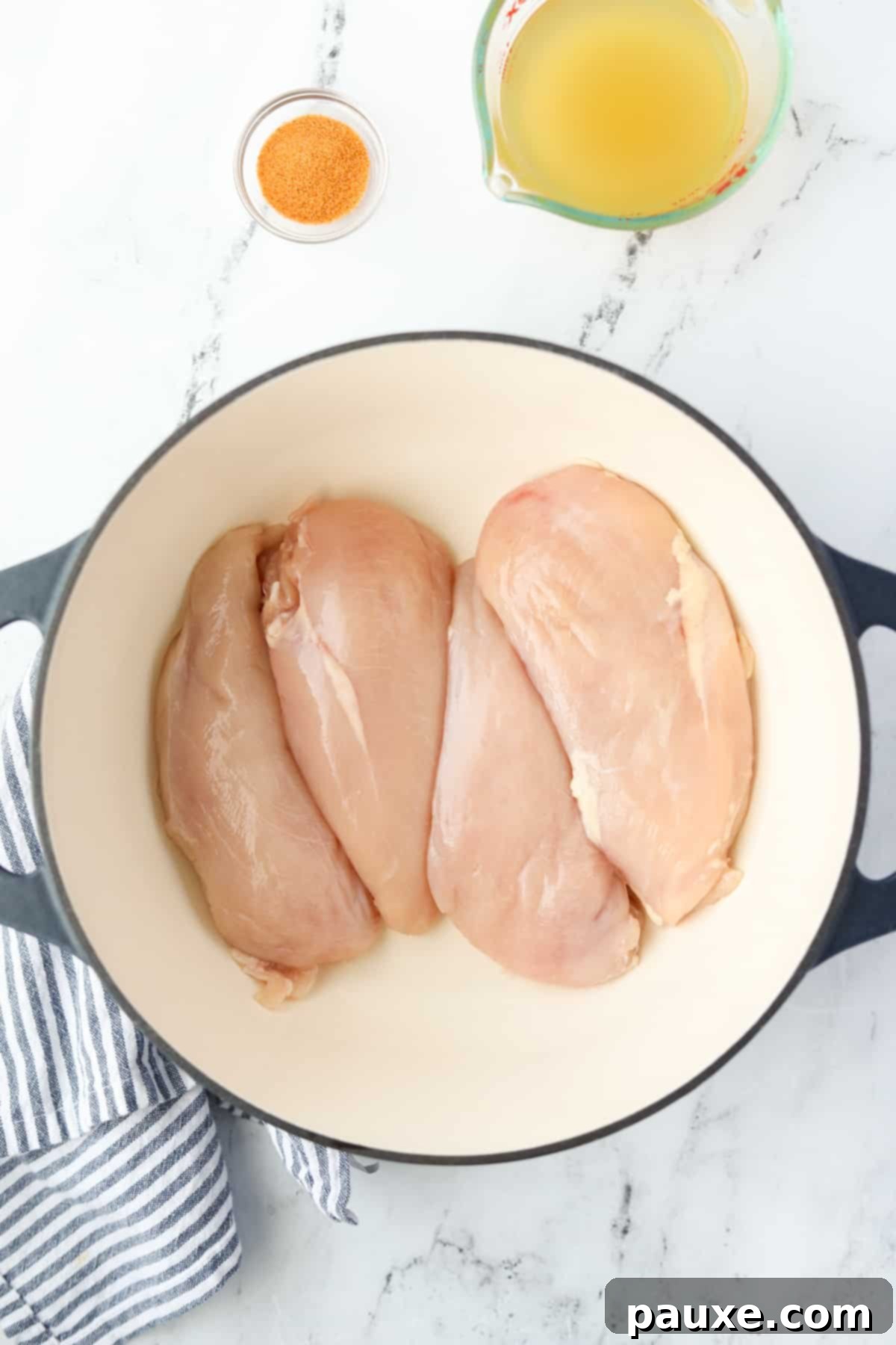 Ultimate Dutch Oven Pulled Chicken 4 A Dutch Oven with four raw chicken breasts arranged neatly inside.