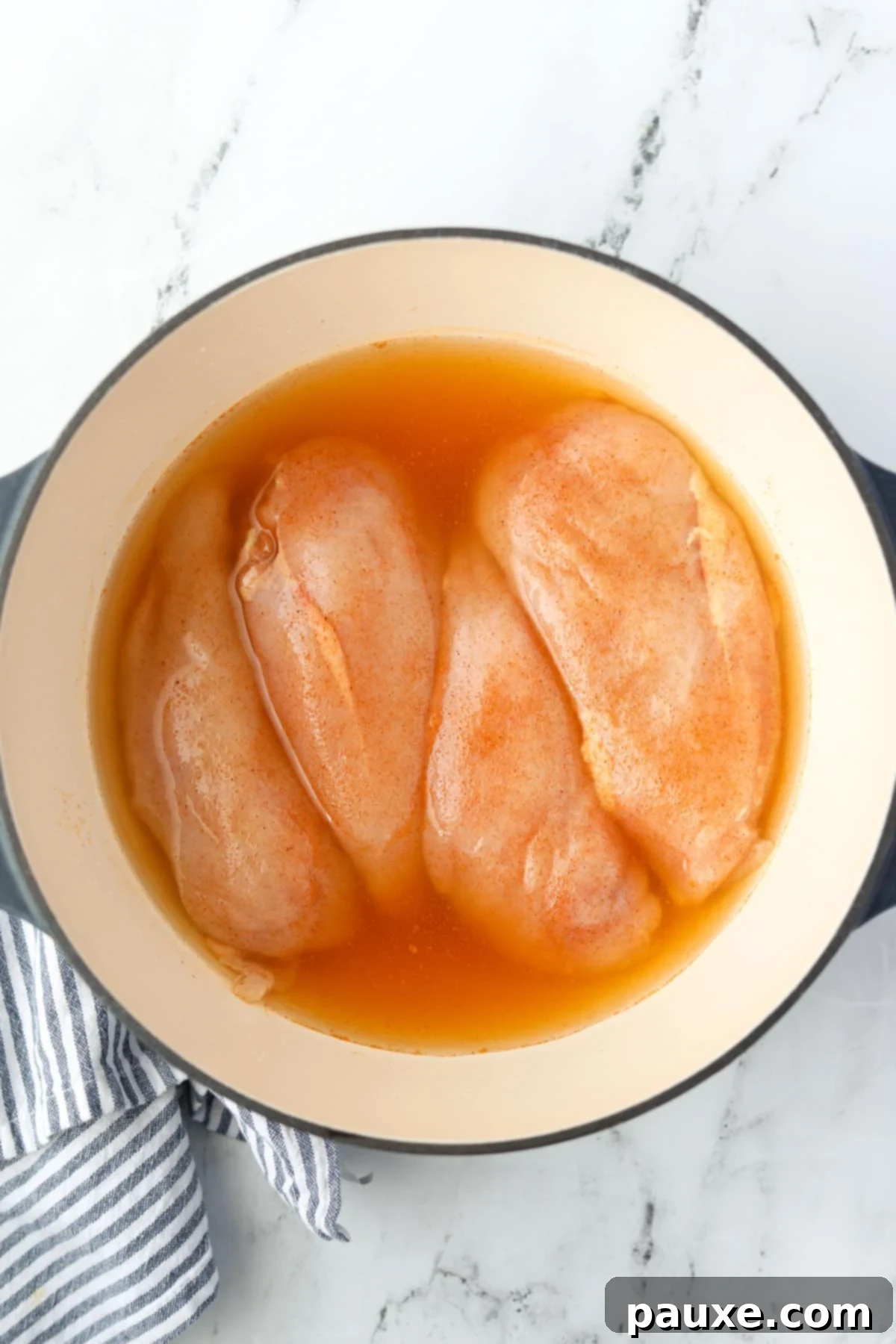 Ultimate Dutch Oven Pulled Chicken 6 A Dutch Oven with four seasoned chicken breasts submerged in chicken broth.