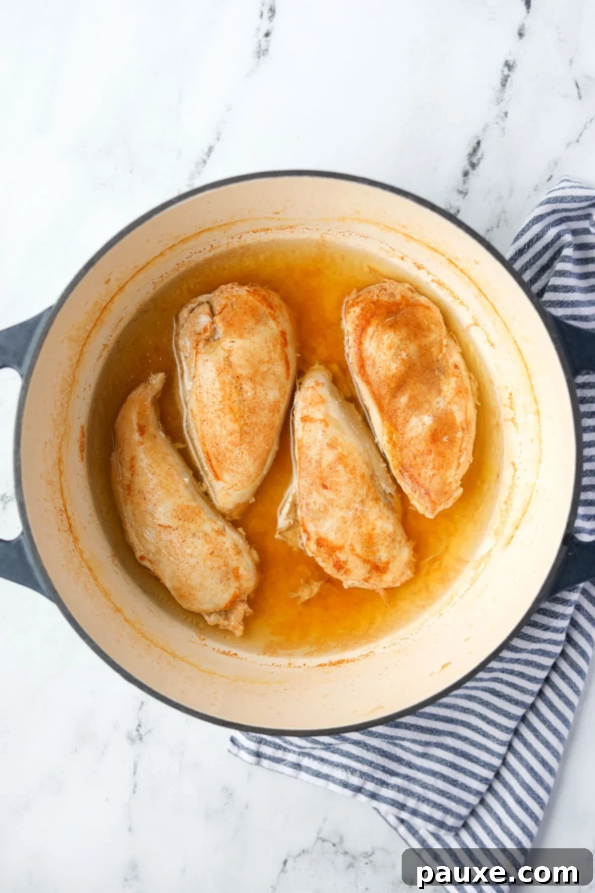 Ultimate Dutch Oven Pulled Chicken 7 Cooked chicken breasts resting in their poaching liquid after being removed from the oven.