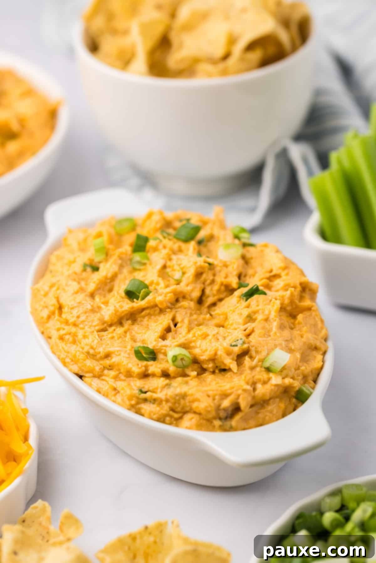 Zesty Slow Cooker Buffalo Chicken Dip 2 An oval baking dish filled with a hot, bubbly, and creamy baked buffalo chicken dip, garnished with fresh herbs.
