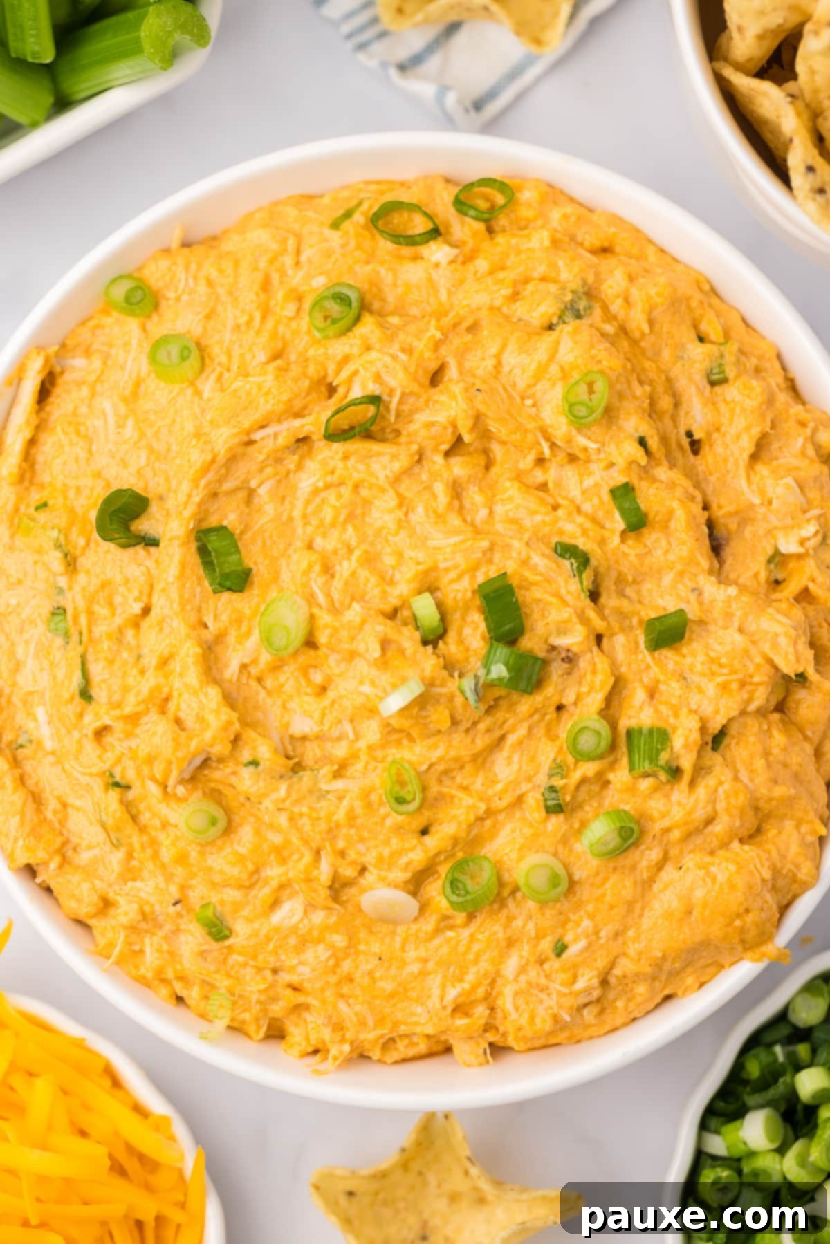 Zesty Slow Cooker Buffalo Chicken Dip 12 A close-up shot of a bowl of creamy chicken dip, beautifully garnished with vibrant chopped green onions, ready to be enjoyed.