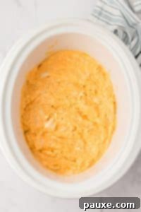 Zesty Slow Cooker Buffalo Chicken Dip 20 A white crock pot filled with a cheesy chicken dip.