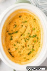 Zesty Slow Cooker Buffalo Chicken Dip 22 A white crock pot with a cheesy chicken dip inside.