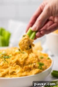 Zesty Slow Cooker Buffalo Chicken Dip 23 Dipping a celery stick into a bowl of buffalo chicken dip.