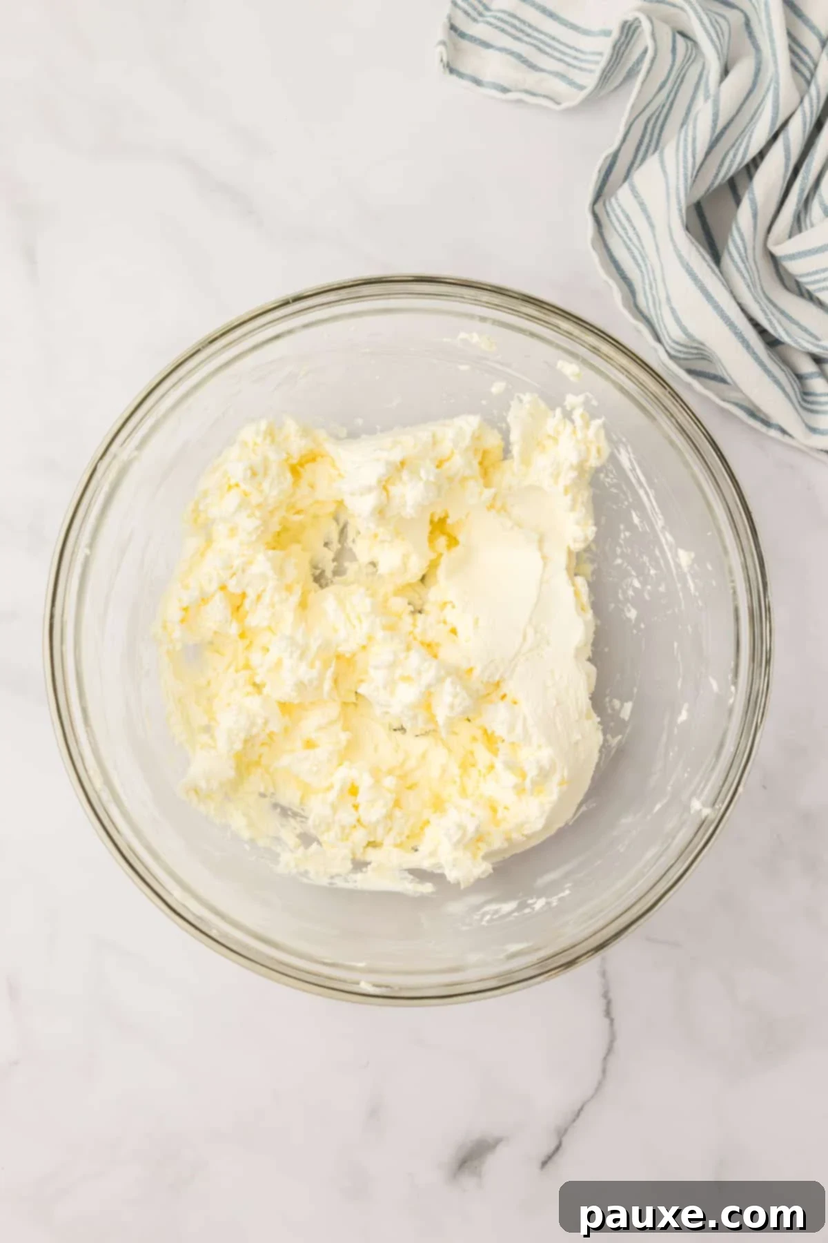 Zesty Slow Cooker Buffalo Chicken Dip 4 A large glass bowl containing softened cream cheese, ready for mixing.