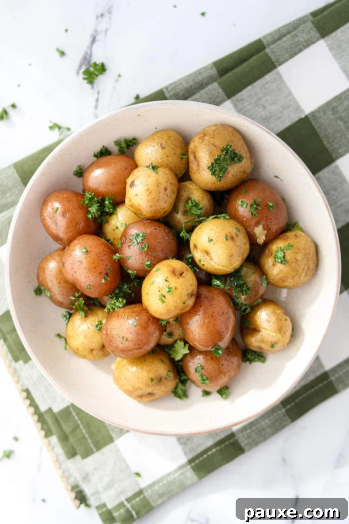 Perfect Instant Pot Baby Potatoes 6 A close-up view of a serving bowl filled with golden, buttered baby potatoes, garnished with vibrant green parsley, highlighting their tender texture.