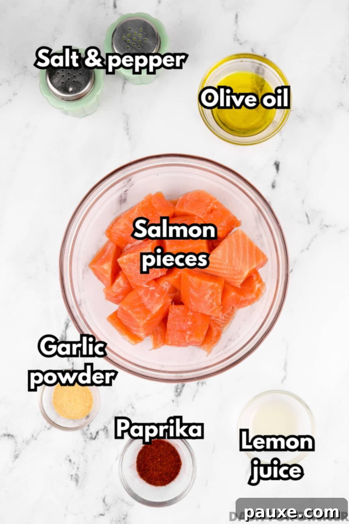 Air-Fried Salmon Nuggets 3 A collection of ingredients laid out: salmon cubes, olive oil, garlic powder, paprika, lemon juice, salt, and black pepper.