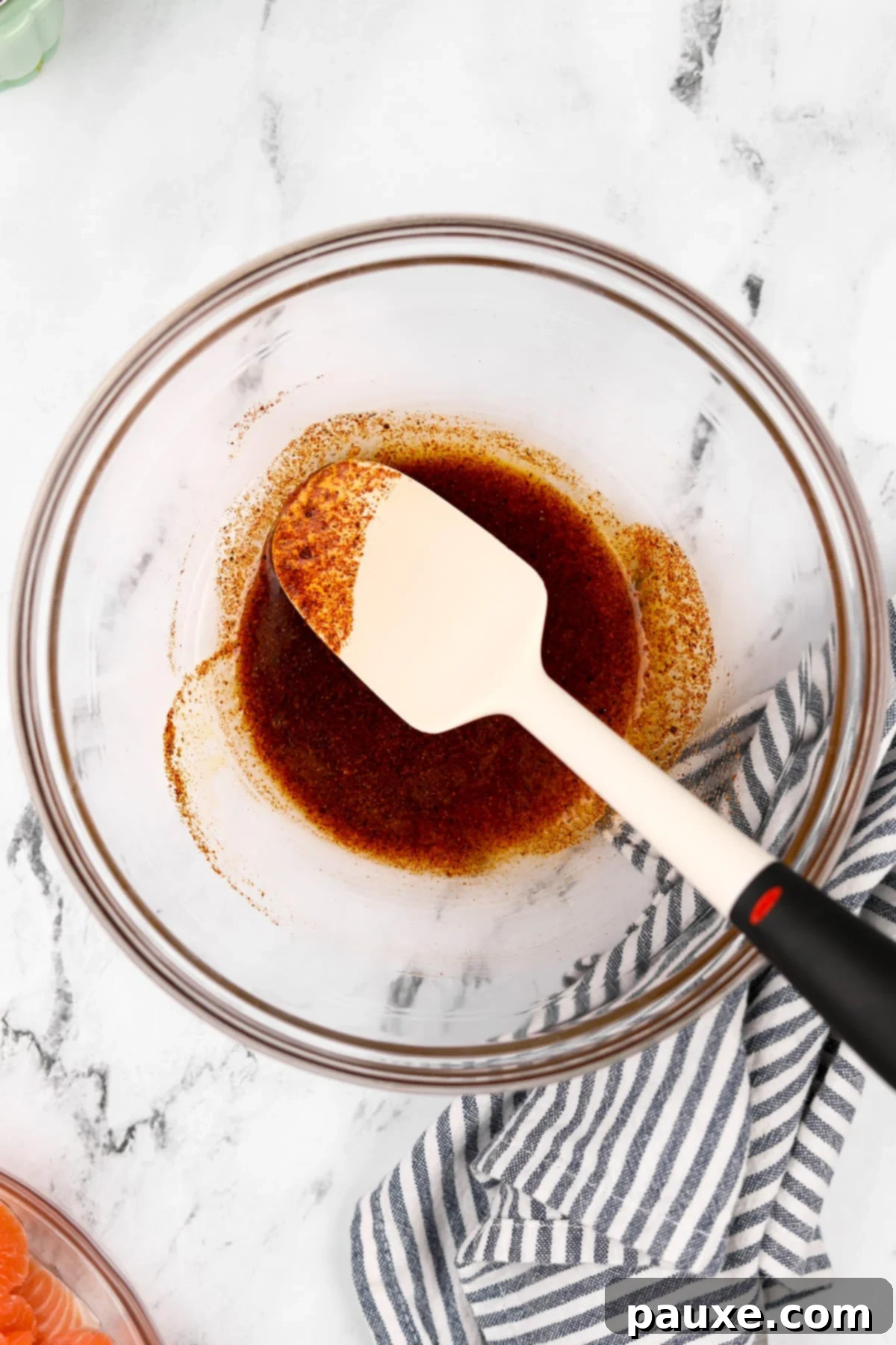 Air-Fried Salmon Nuggets 4 A glass bowl containing olive oil, lemon juice, garlic powder, paprika, salt, and pepper being stirred together.