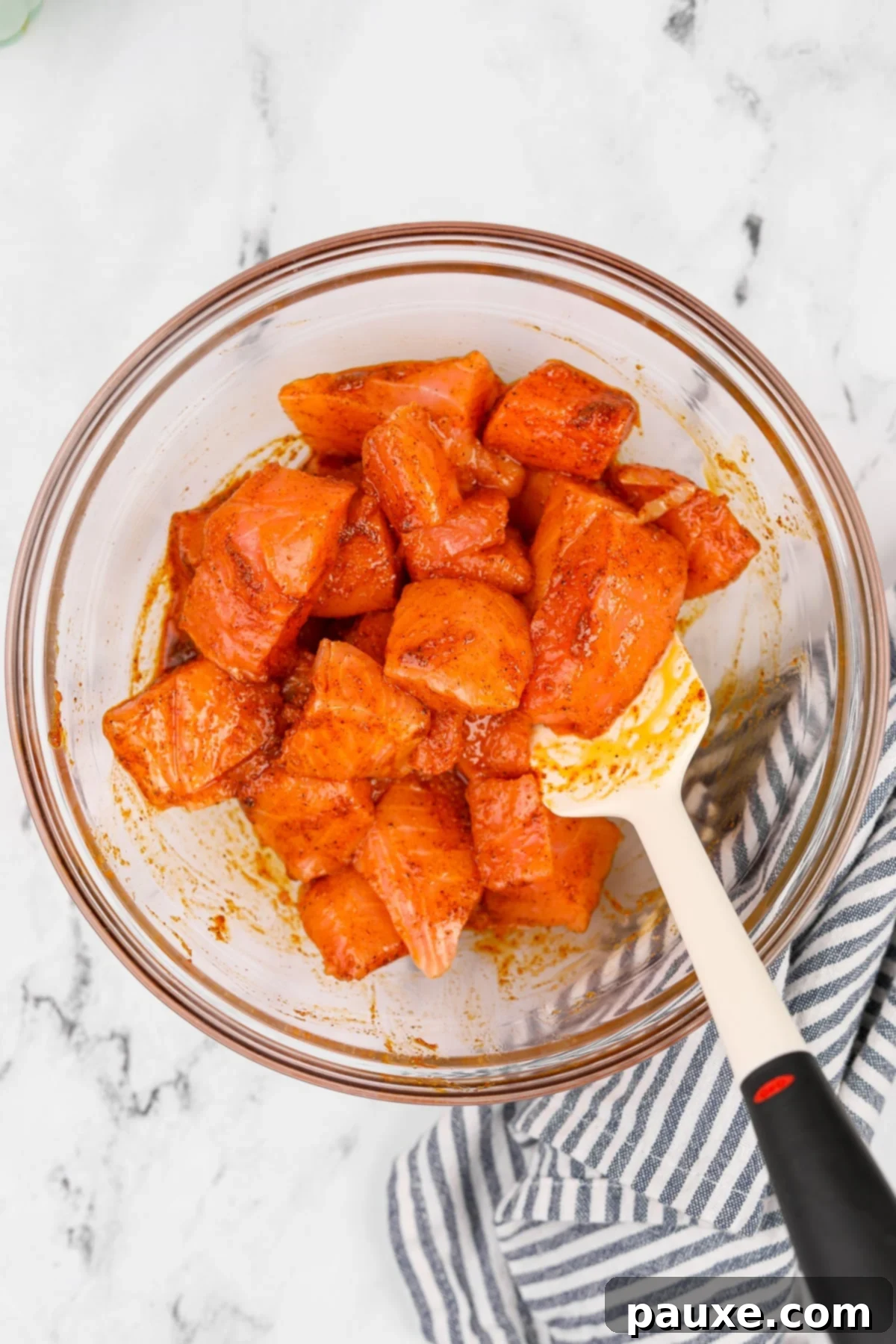 Air-Fried Salmon Nuggets 5 Cubed salmon pieces thoroughly coated with seasonings and olive oil in a glass bowl.