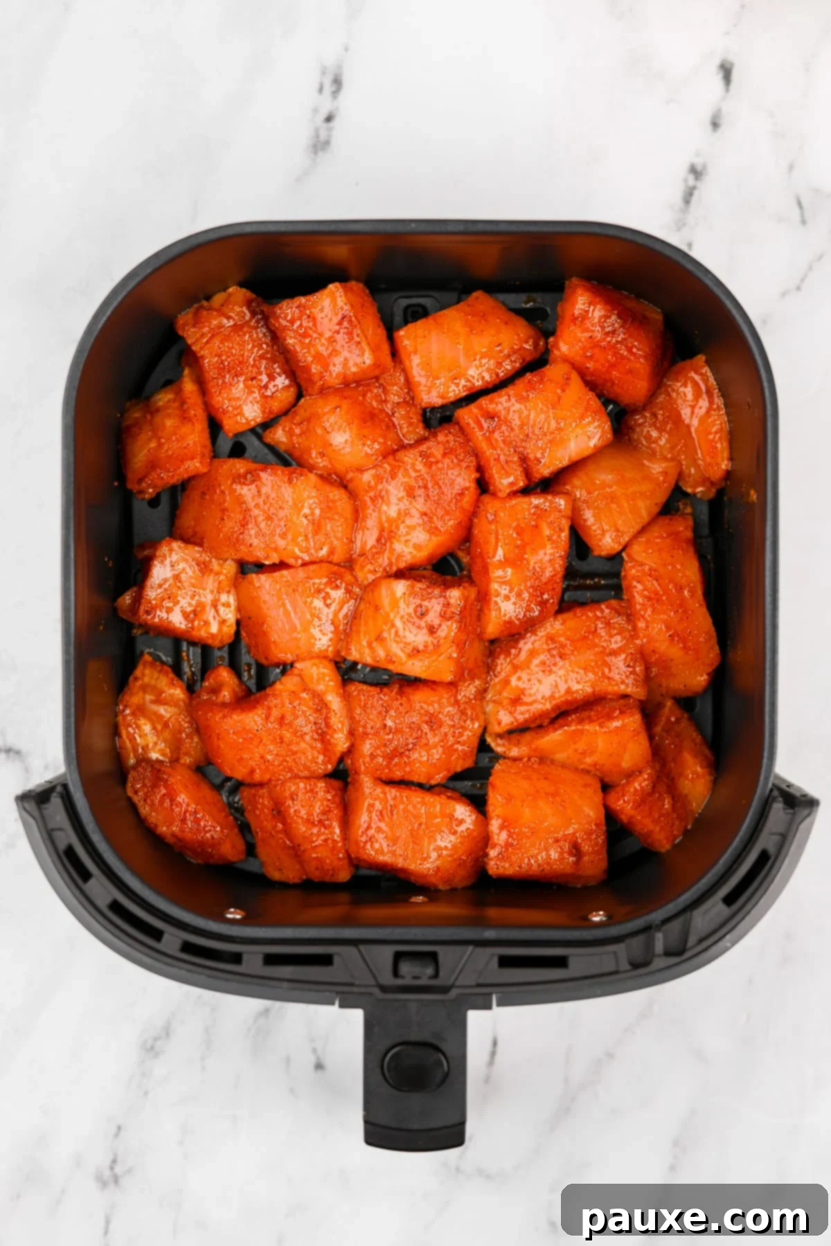 Air-Fried Salmon Nuggets 6 An air fryer basket loaded with seasoned salmon cubes arranged in a single, even layer.