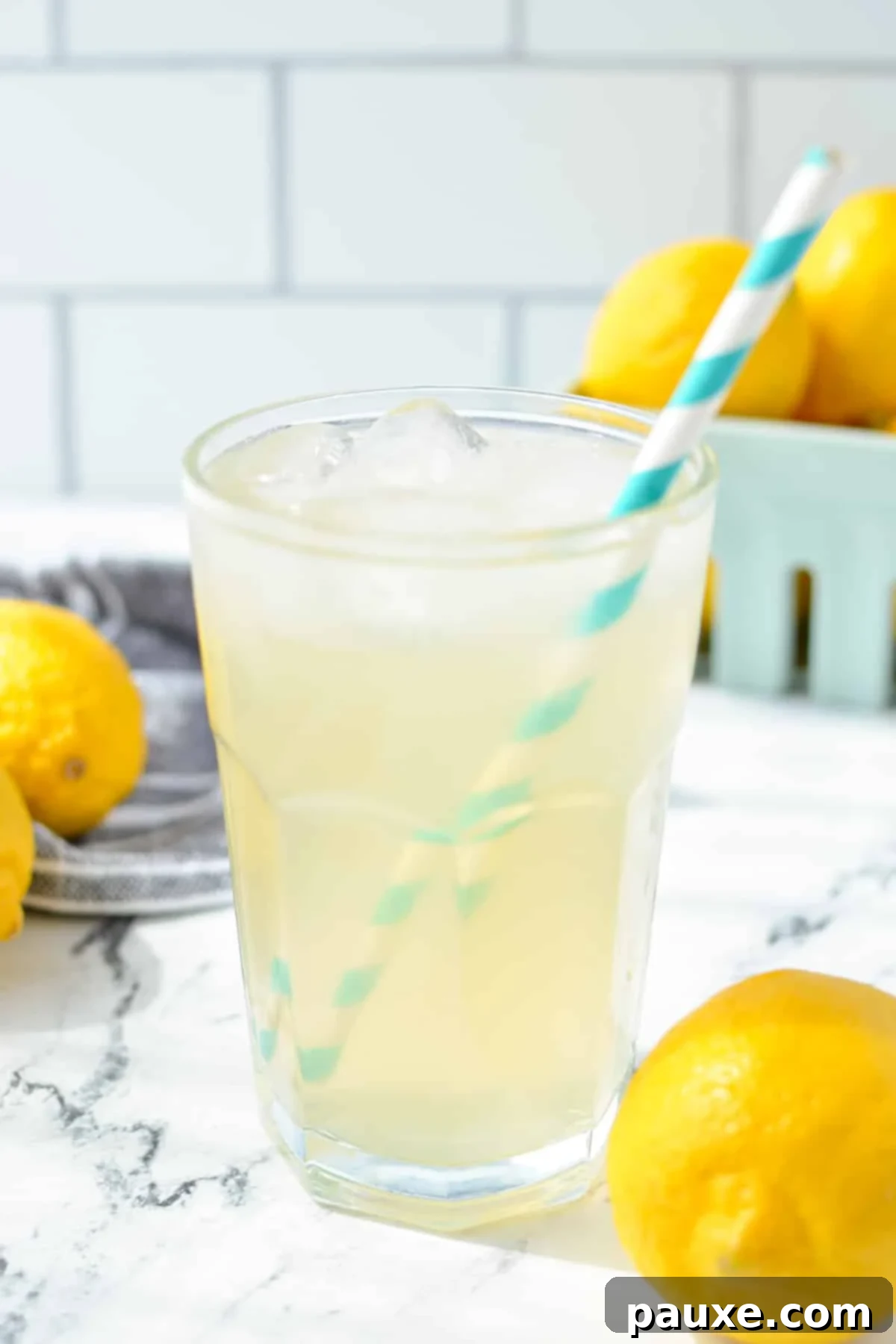 Solo Lemonade Delight 7 A glass of lemonade with a paper straw with lemons in the background.