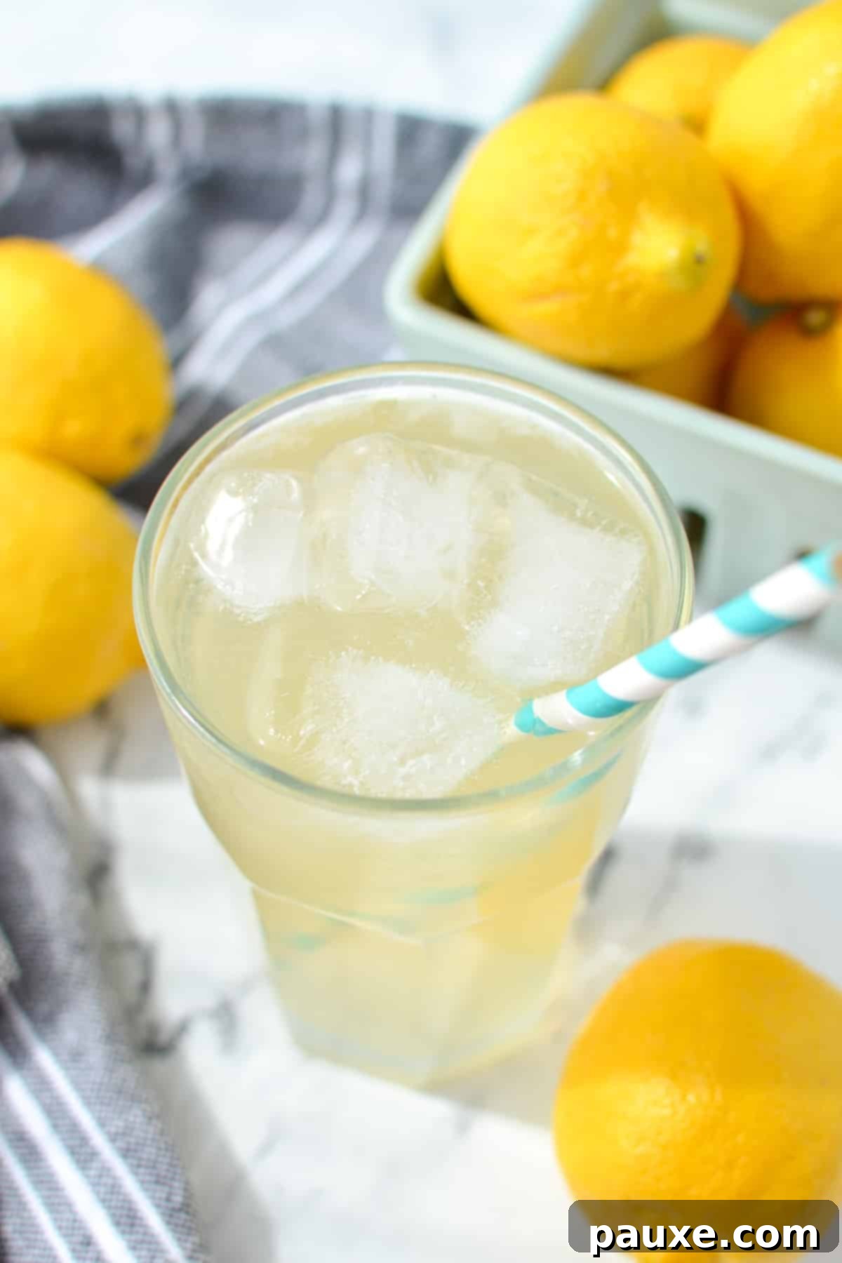 Solo Lemonade Delight 8 Lemonade in a glass filled with ice, with fresh lemons in the background.