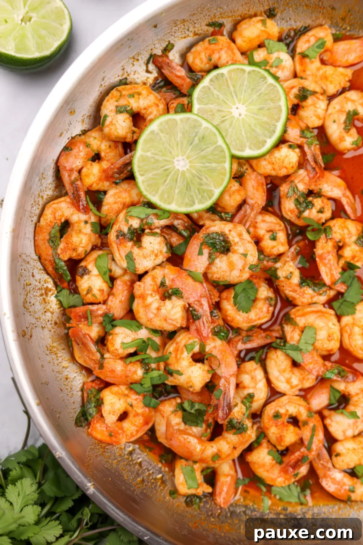Zesty Cilantro Lime Shrimp 2 A skillet filled with cooked shrimp, garnished with fresh cilantro and lime slices, showcasing a vibrant, zesty marinade.