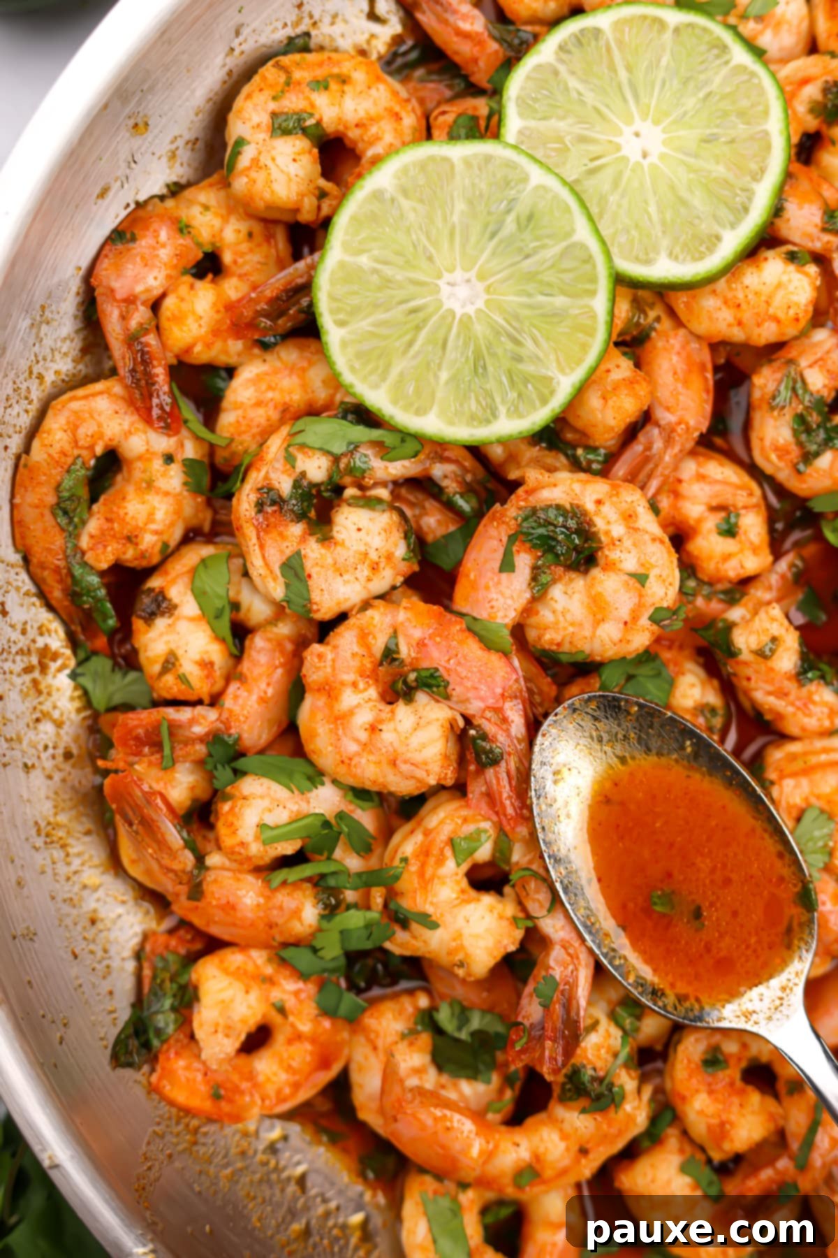 Zesty Cilantro Lime Shrimp 6 A spoon gathering delicious sauce from a skillet full of cooked shrimp, highlighting the rich and zesty marinade.