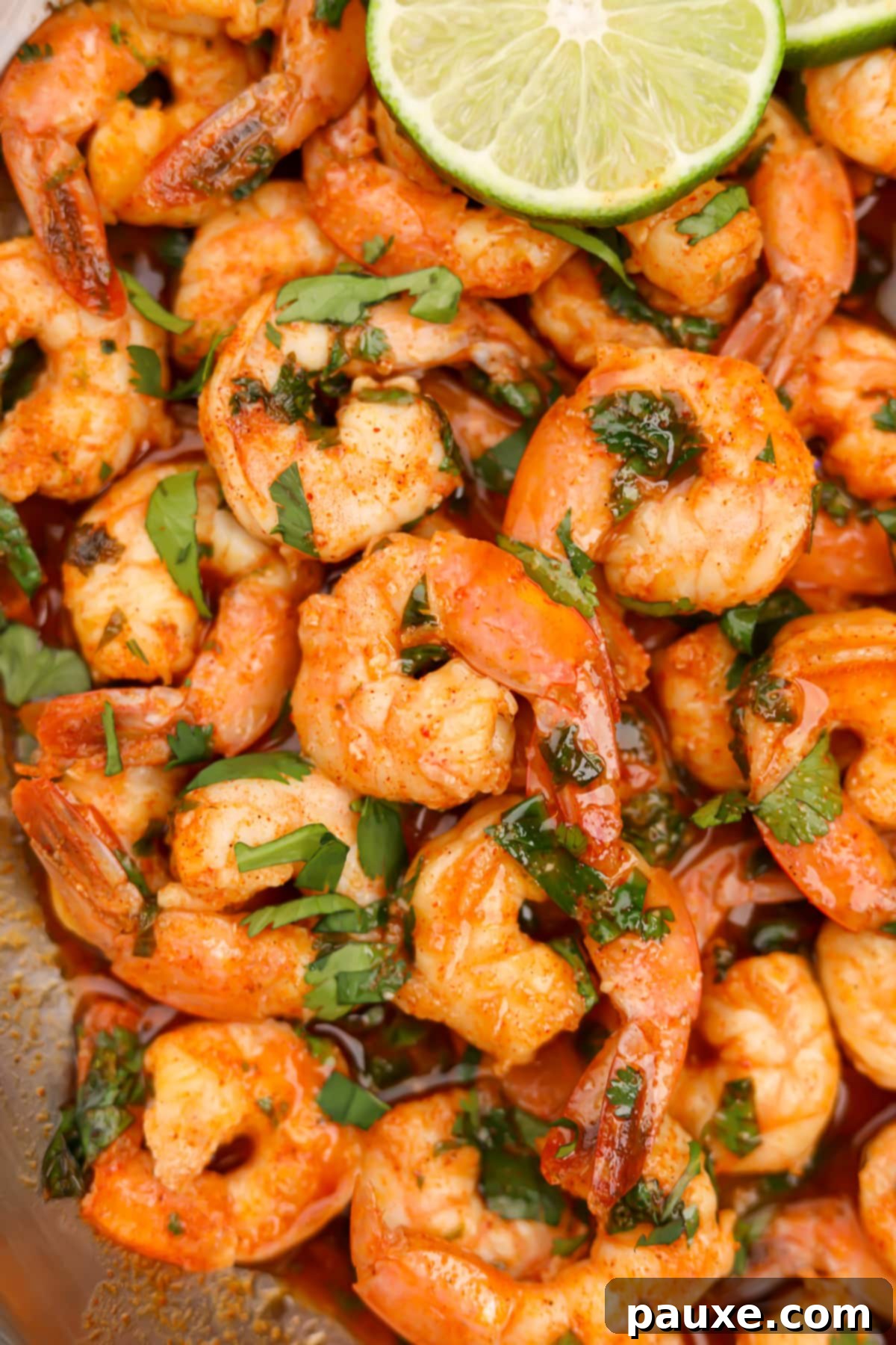 Zesty Cilantro Lime Shrimp 7 A beautifully arranged pile of cooked cilantro lime shrimp, generously coated in sauce and garnished with fresh cilantro leaves and bright lime slices.