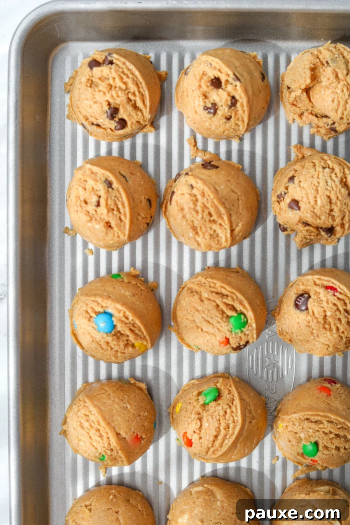 Guilt-Free Protein Cookie Dough 11 A baking sheet laden with various scooped protein cookie dough portions, showcasing the different mix-ins and consistent shapes, ready for chilling and enjoyment.