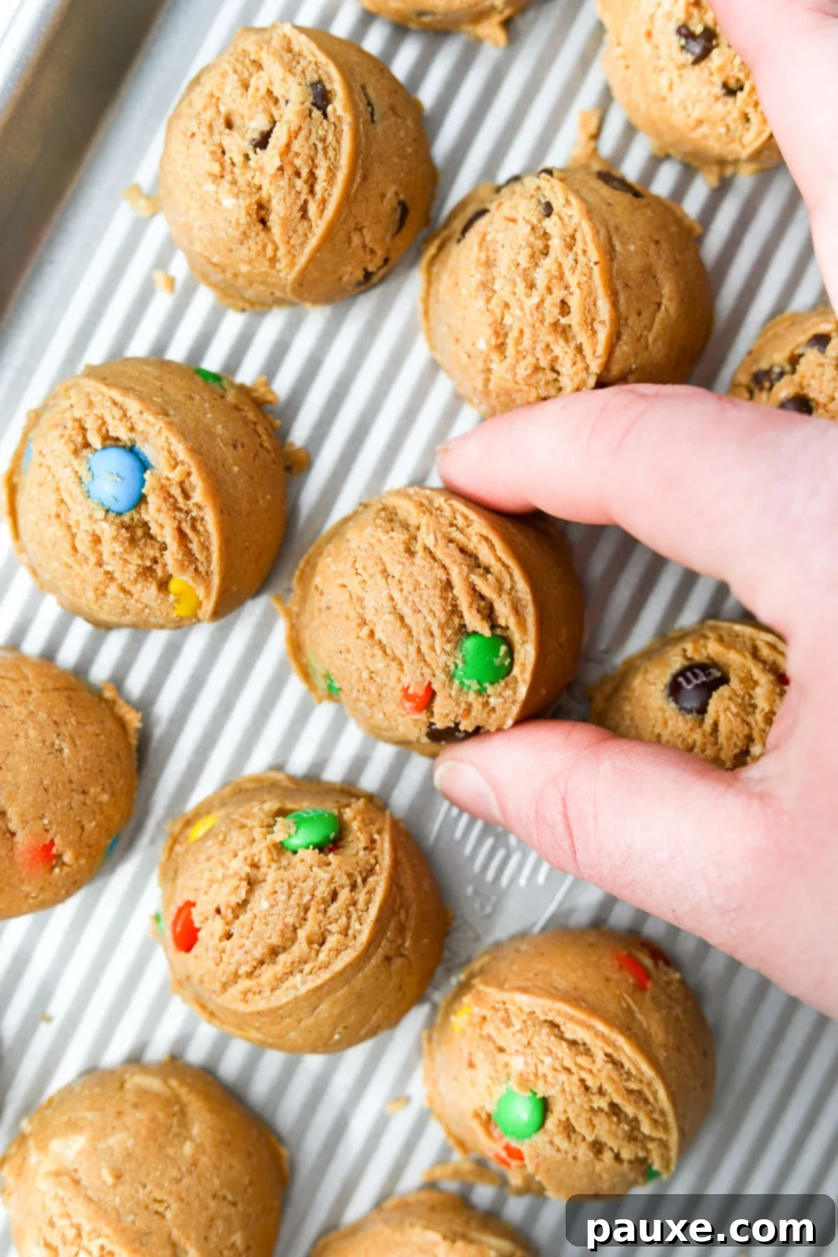 Guilt-Free Protein Cookie Dough 12 A hand gently placing a perfectly formed mound of protein cookie dough onto a baking tray, ready for the chilling process.