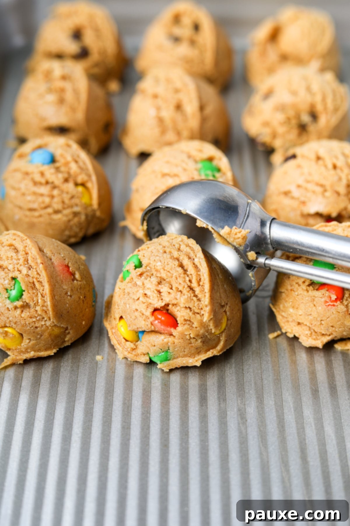 Guilt-Free Protein Cookie Dough 9 A freshly scooped portion of protein cookie dough being carefully placed onto a parchment-lined baking sheet, demonstrating the ease of preparation.