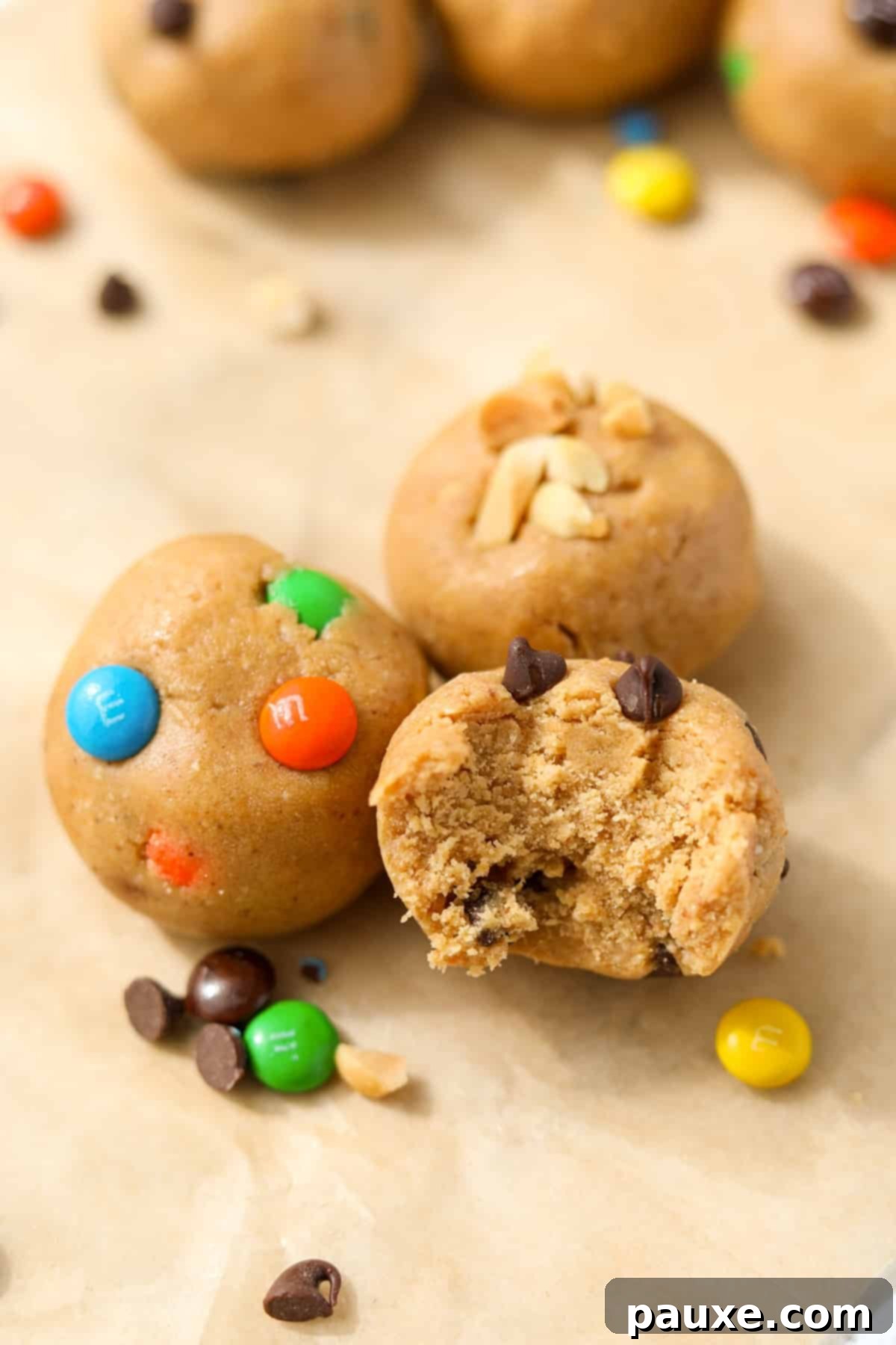 Protein-Packed Cookie Dough Bites 11 Three protein cookie dough balls featuring M&M's, chocolate chips, and chopped peanuts, ready to be enjoyed.