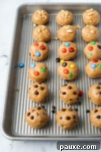Protein-Packed Cookie Dough Bites 19 A baking tray with cookie dough balls, featuring chocolate chip, m&m, and chopped peanuts.