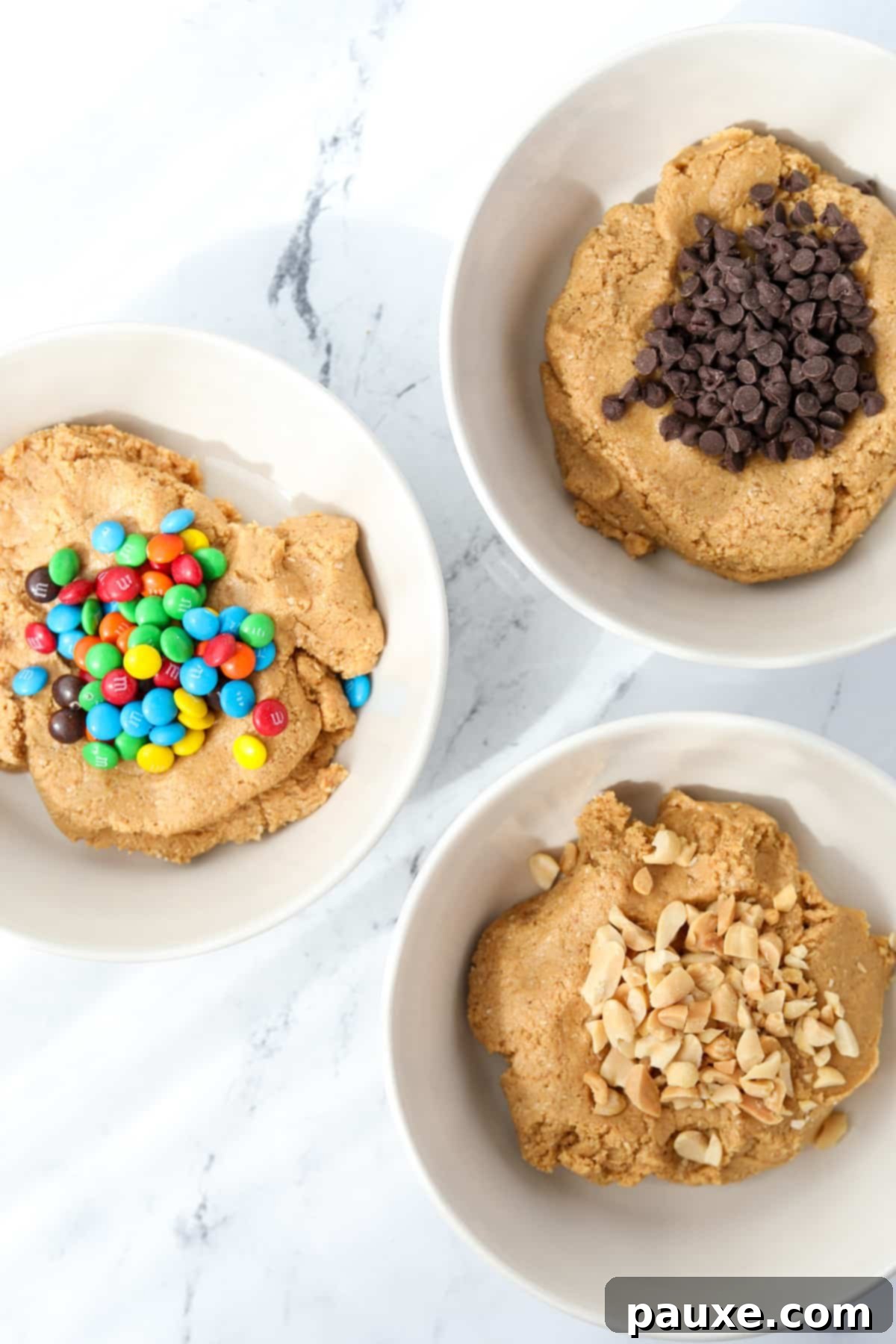 Protein-Packed Cookie Dough Bites 7 Three bowls of cookie dough, each with different mix-ins: chocolate chips, M&M's, and chopped peanuts, ready for rolling.