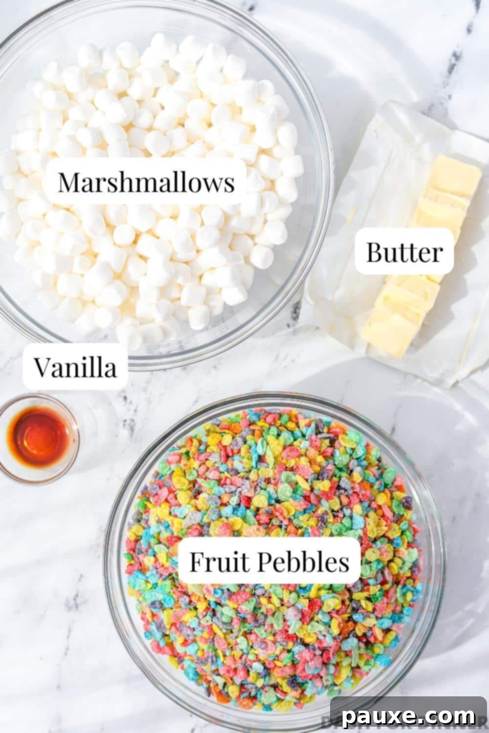 Colorful Pebbles Bars 3 A beautifully arranged flat lay showing a bowl of mini marshmallows, a box of Fruity Pebbles cereal, a stick of butter, and a bottle of vanilla extract – all the key ingredients for making Fruity Pebbles Treats.