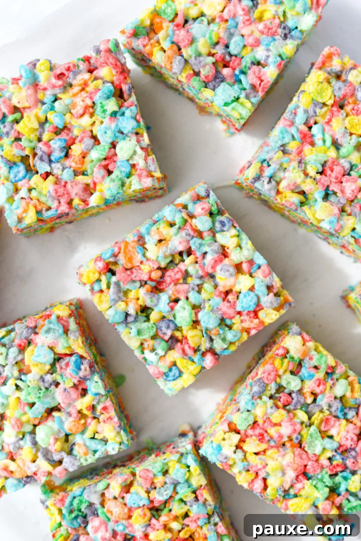 Colorful Pebbles Bars 8 Individual Fruity Pebbles treats artfully arranged on a clean white background, highlighting their vibrant colors and perfect square shapes.