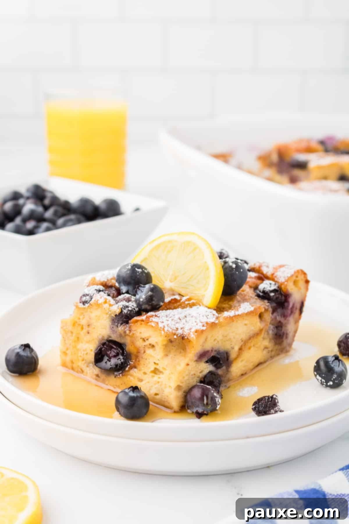 Overnight Brioche French Toast Bake 2 A golden-brown slice of Brioche French Toast Casserole, topped with vibrant fresh blueberries and a light dusting of powdered sugar, served on a white plate.
